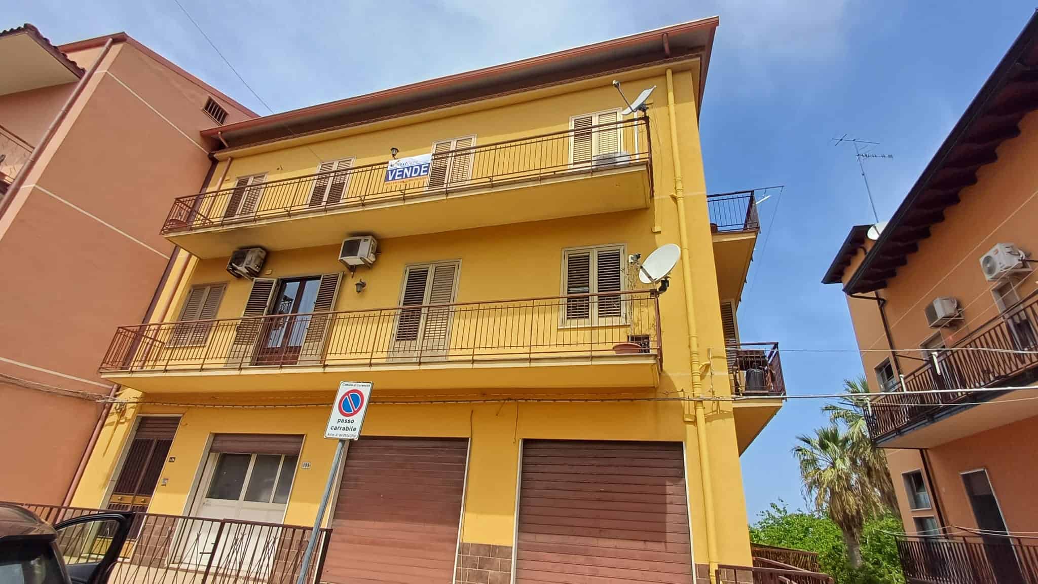 Appartamento in vendita in edificio giallo con tre piani, balconi e aria condizionata, situato in zona residenziale soleggiata e tranquilla, ideale per famiglie o investitori immobiliari.
