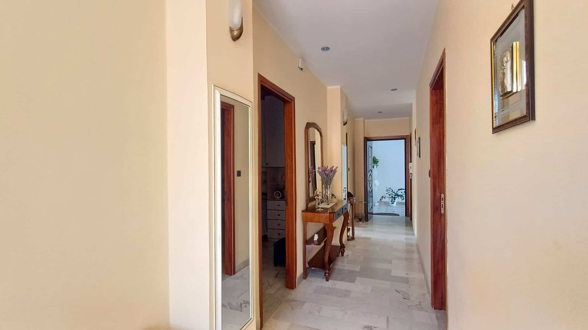 Pannello di ingresso luminoso con pareti beige, arredi eleganti e accessori decorativi, ideale per case in vendita o in affitto a NextCasa, agenzia immobiliare specializzata in immobili di qualità in.