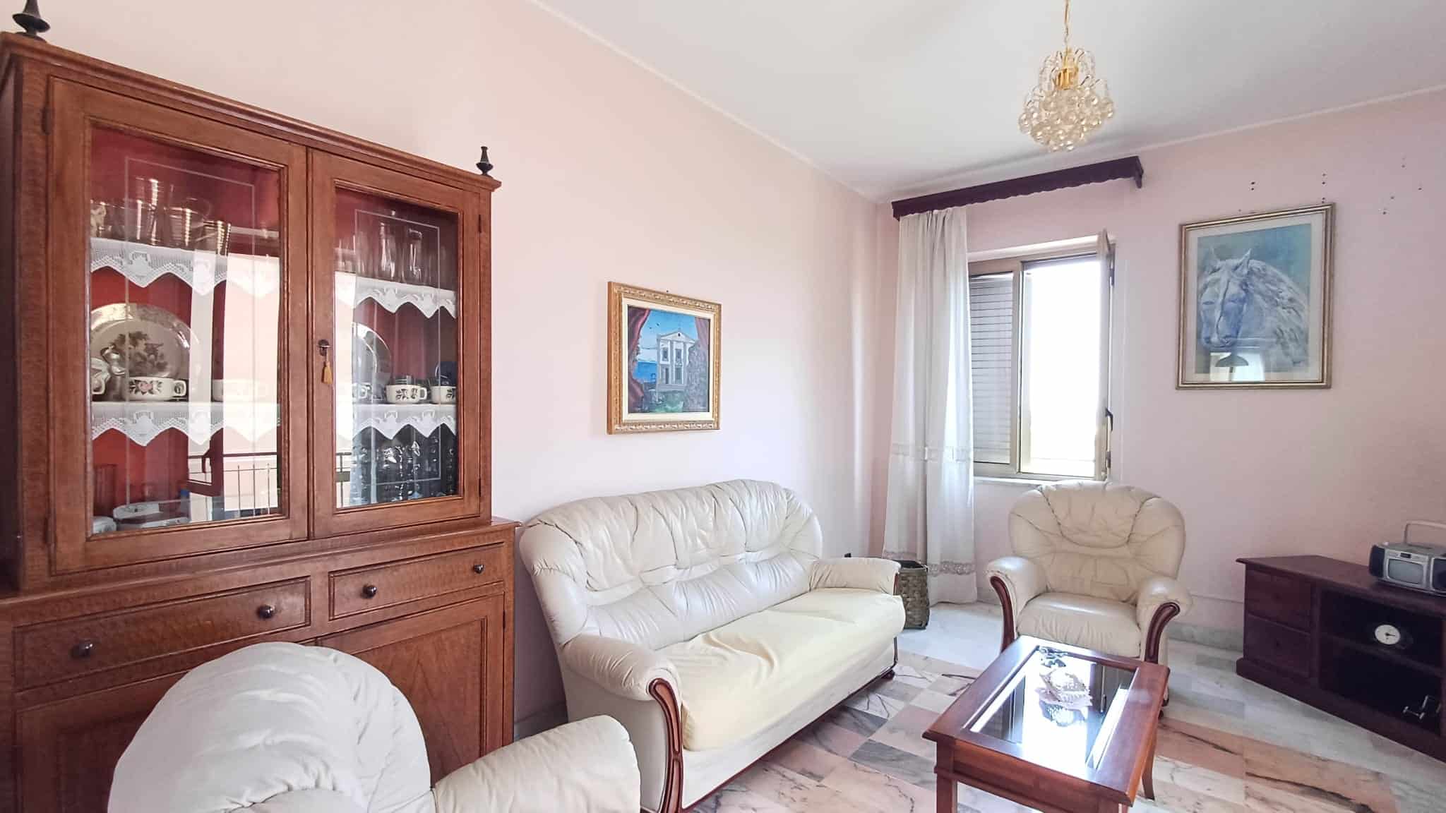 Elegante soggiorno con divani in pelle beige, mobile in legno, e decorazioni moderne, ideale per vivere momenti di relax e convivialità in un ambiente accogliente e luminoso.
