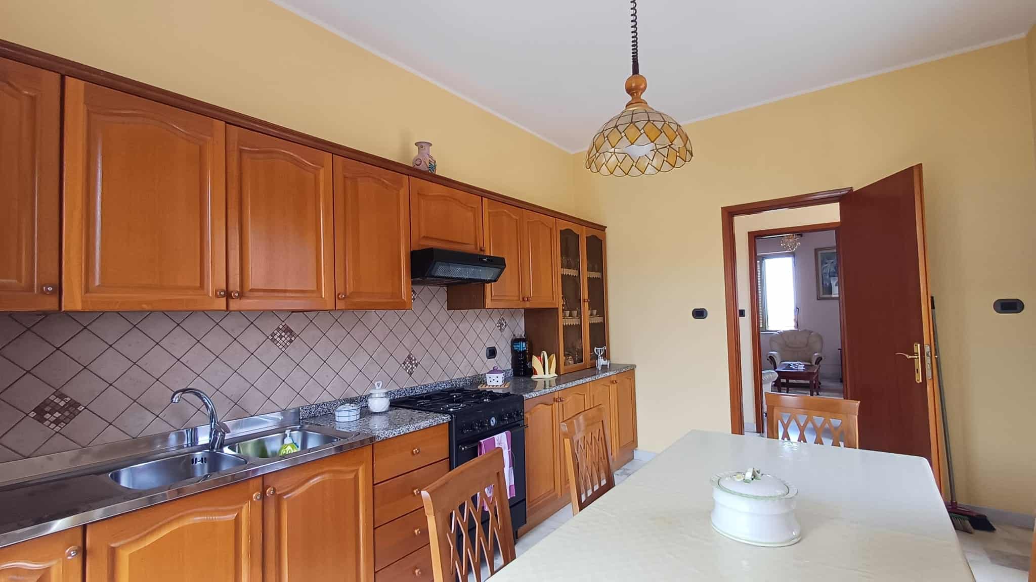 Lavastoviglie e piano cottura in cucina con mobili in legno, ideale per case in vendita o affitto a NextCasa. Cucina spaziosa e funzionale con dettagli eleganti e pratici.