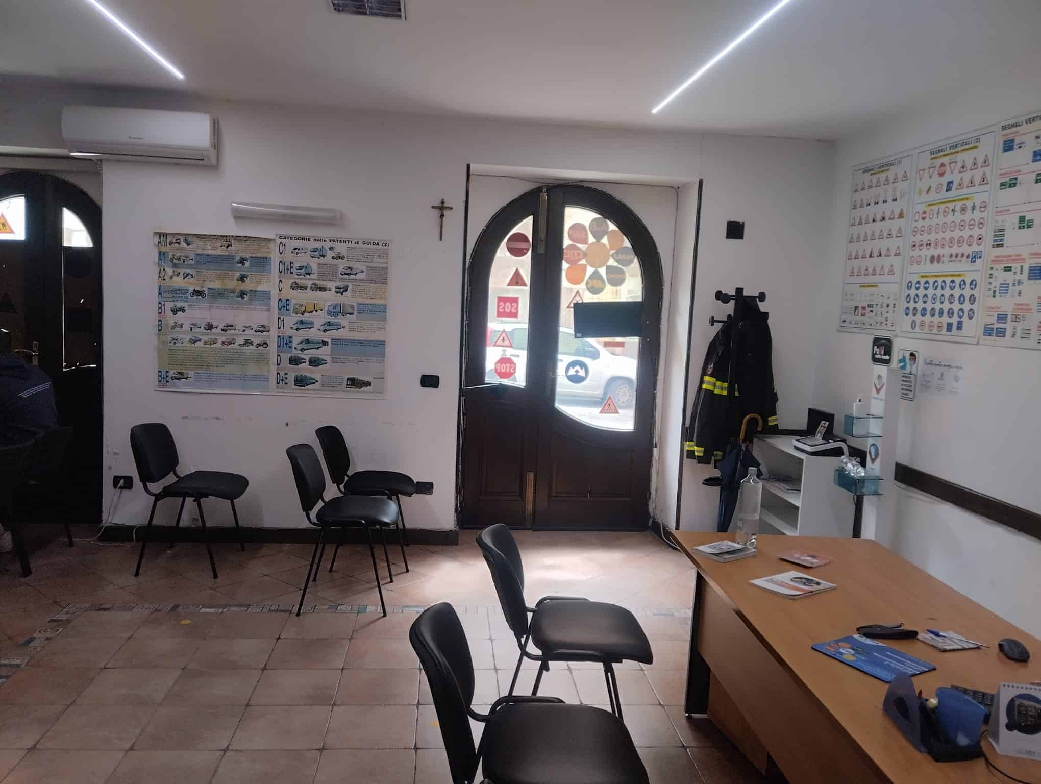 Assistenza clienti e sala d'attesa in ufficio immobiliare NextCasa con arredi moderni e poster informativi sulle proprietà immobiliari.