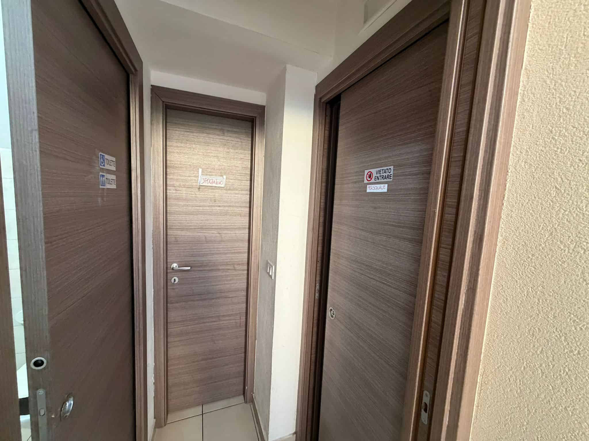 Porta blindata in legno con serrature di sicurezza, ideale per ingressi residenziali e uffici, in un ambiente interno moderno e ben illuminato.