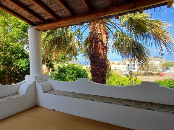 Vista panoramica di una terrazza con palme e vista mare, ideale per relax e convivialità, in un contesto residenziale mediterraneo. Perfetta per case vacanza o appartamenti in affitto a NextCasa.