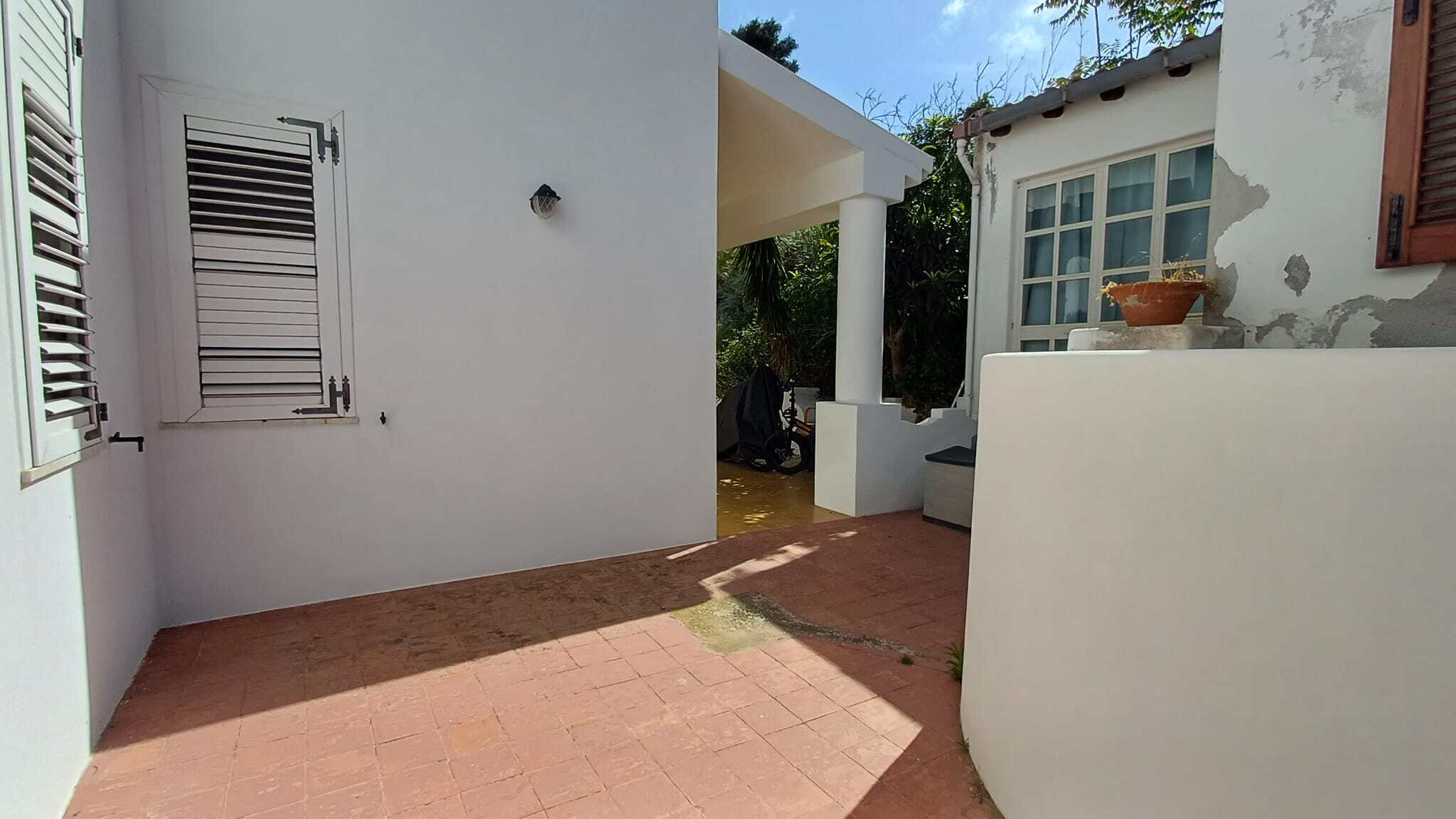 Ampia terrazza esterna con pavimentazione in terracotta, zona relax con sedie e ombrellone, ideale per vivere momenti all'aperto in un ambiente tranquillo e luminoso.