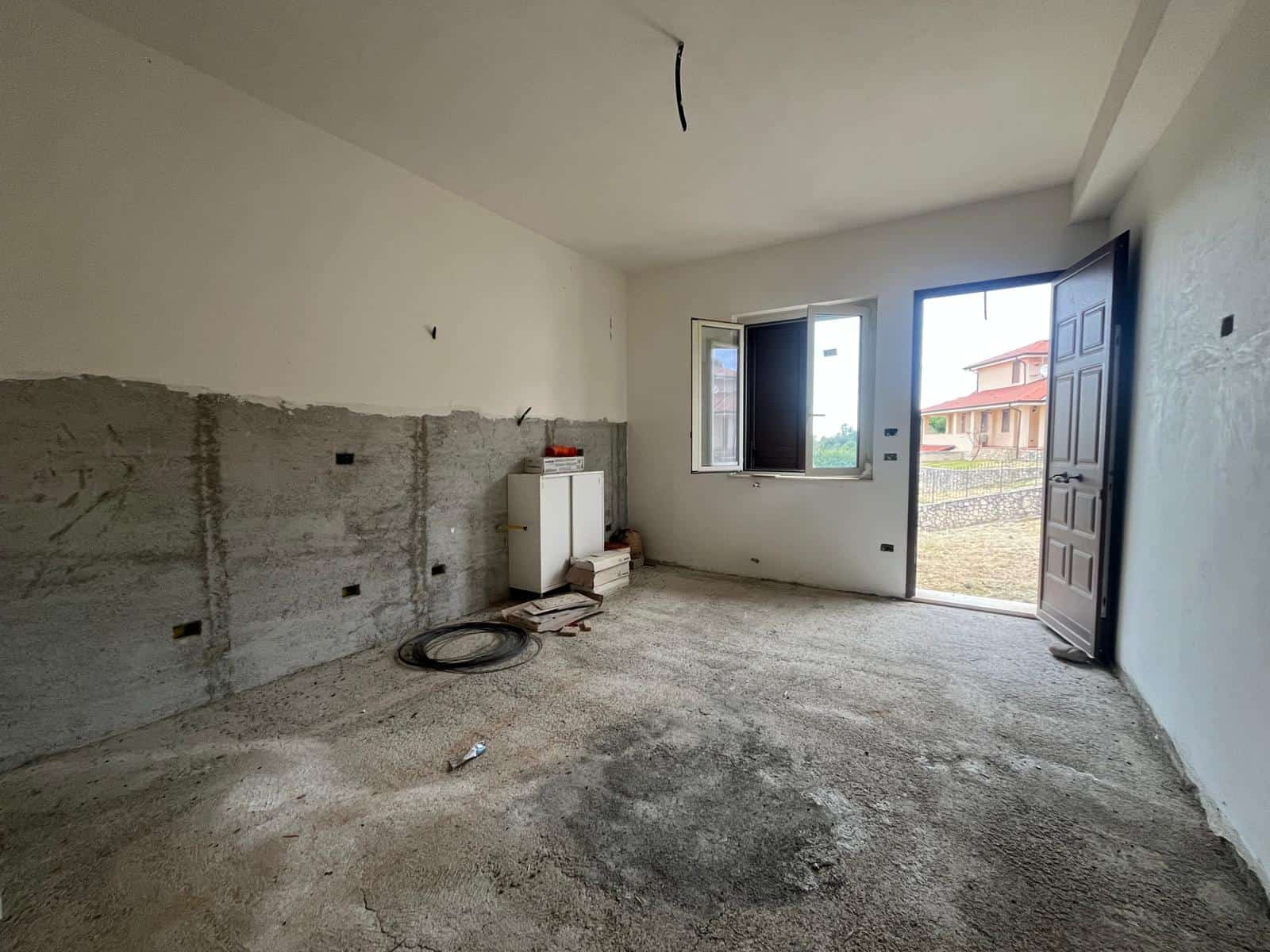 Aggiunta di un'immagine di un interno di una casa in fase di ristrutturazione, con pareti in costruzione e finestre che affacciano su un cortile esterno. Ideale per servizi di compravendita e ristrutt.