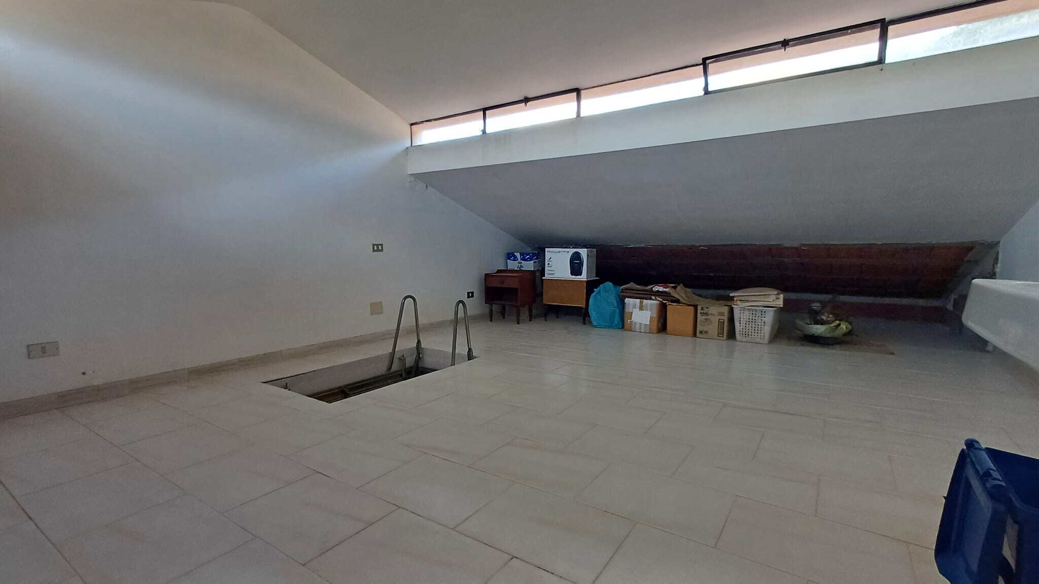 Escaletta in metallo e spazio vuoto in un attico con vista panoramica, ideale per ristrutturazione e arredamento moderno. Ambienti luminosi e spaziosi, perfetti per creare un soggiorno accogliente e f.