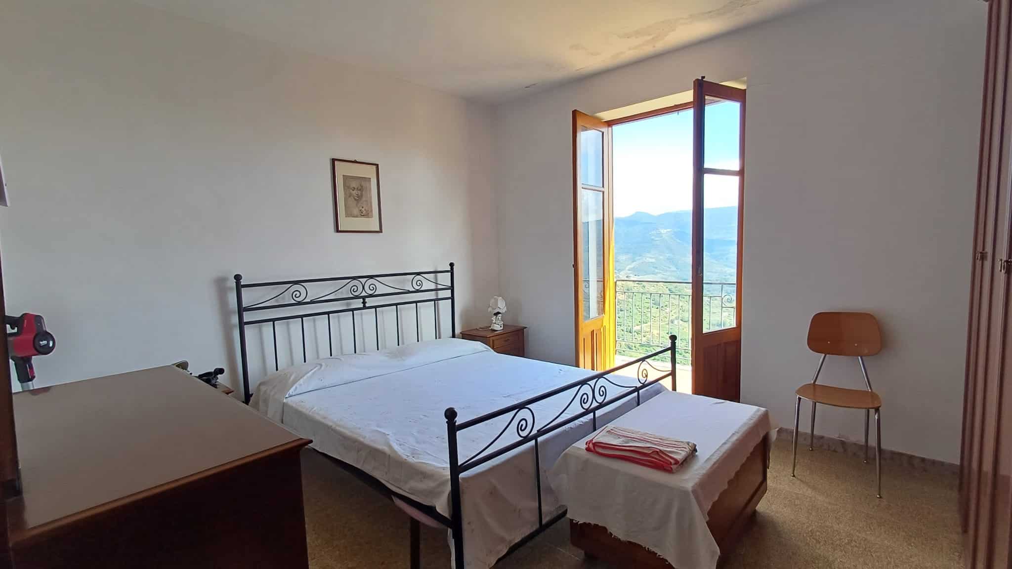 Una stanza da letto luminosa con vista panoramica sulle montagne, arredi semplici e stile minimalista, ideale per case vacanza o residenze in affitto, con accesso a balcone soleggiato e atmosfera acco.