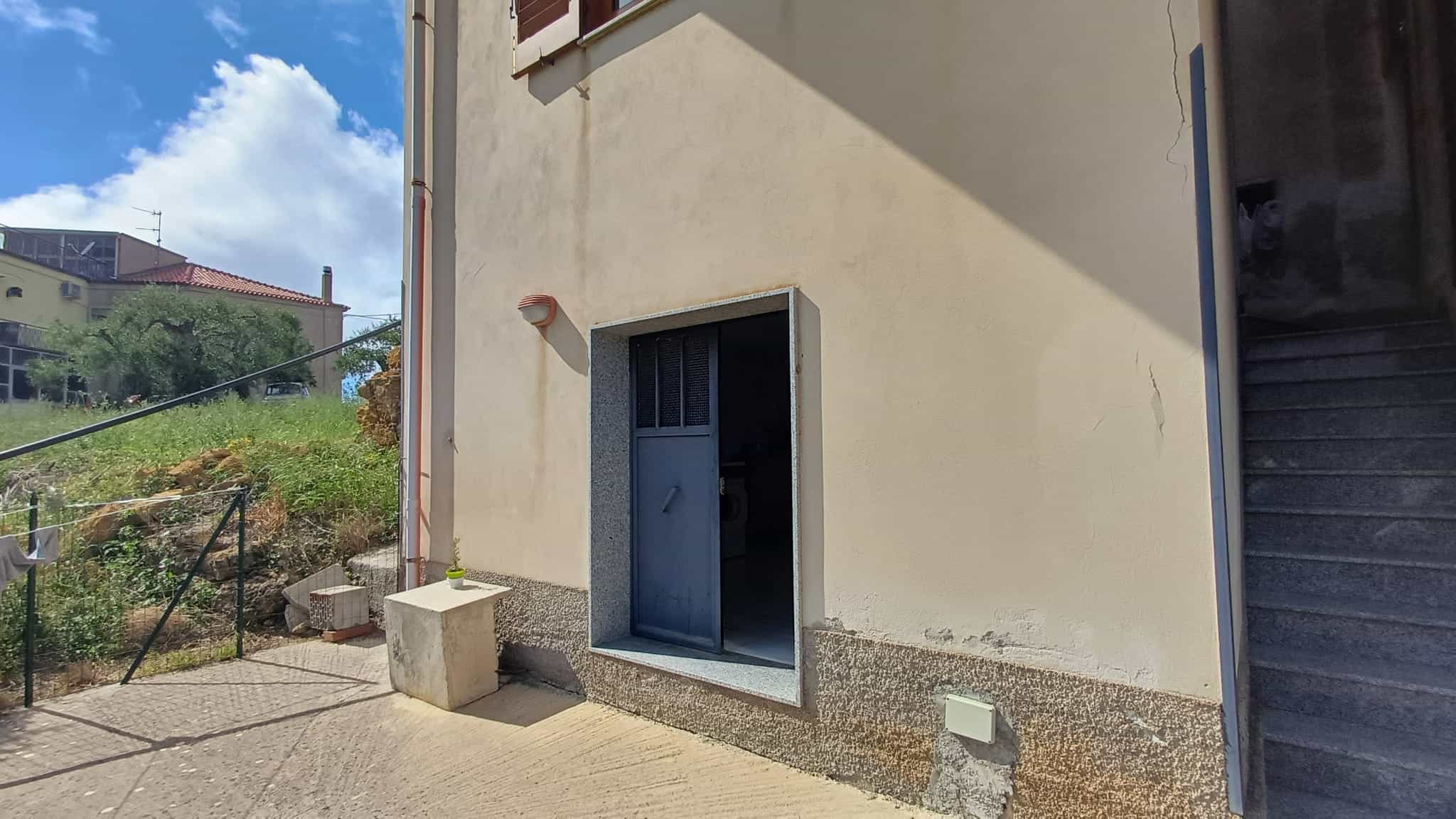 Finestra di servizio in una parete esterna di un edificio residenziale, con vista sul cielo e sul paesaggio circostante, in un ambiente urbano e tranquillo.
