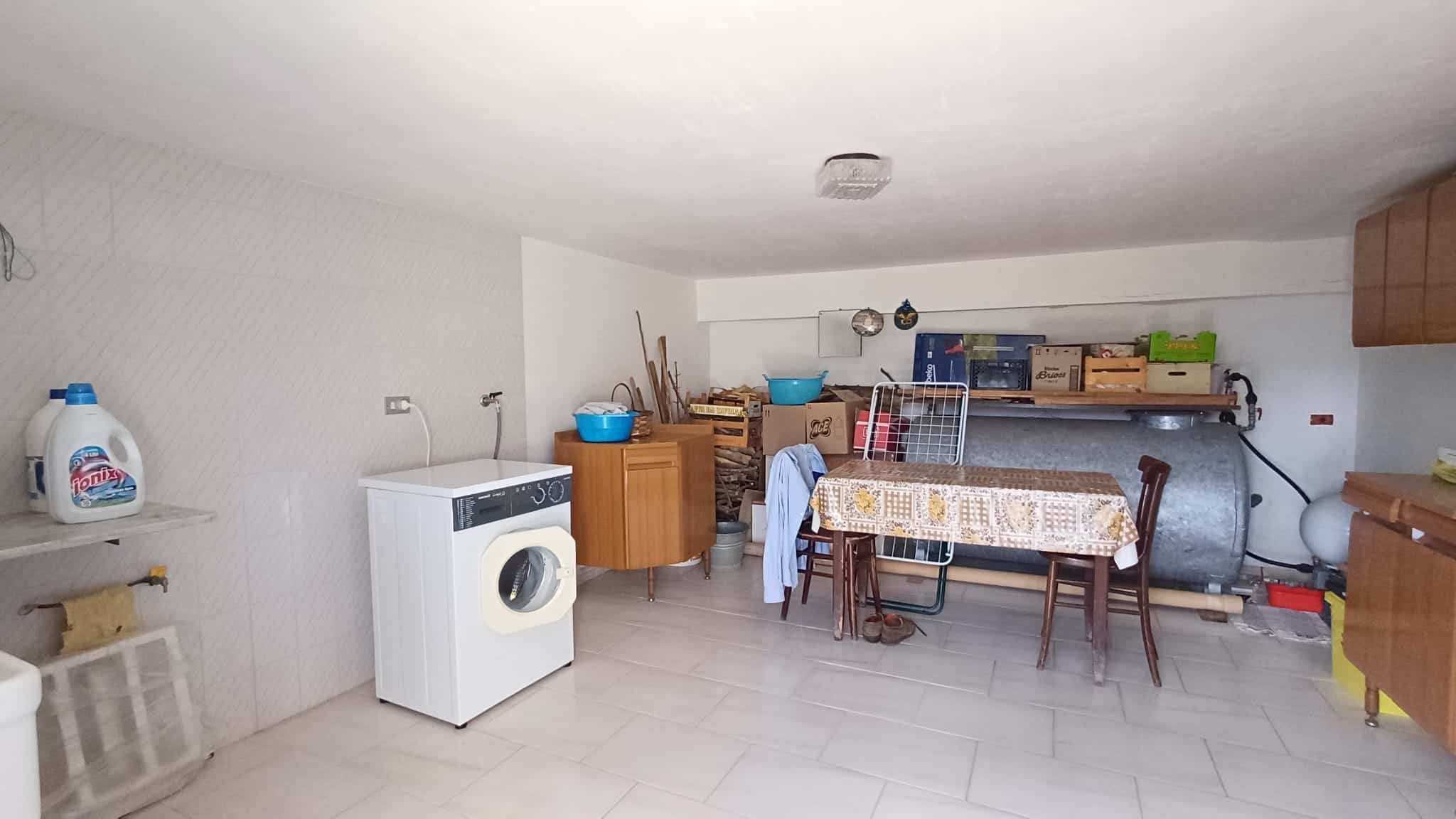 Lavatrice e deposito di attrezzi in un locale di servizio spazioso e ben organizzato, ideale per la gestione domestica e il deposito di strumenti. Ambiente funzionale e pratico, perfetto per le esigen.