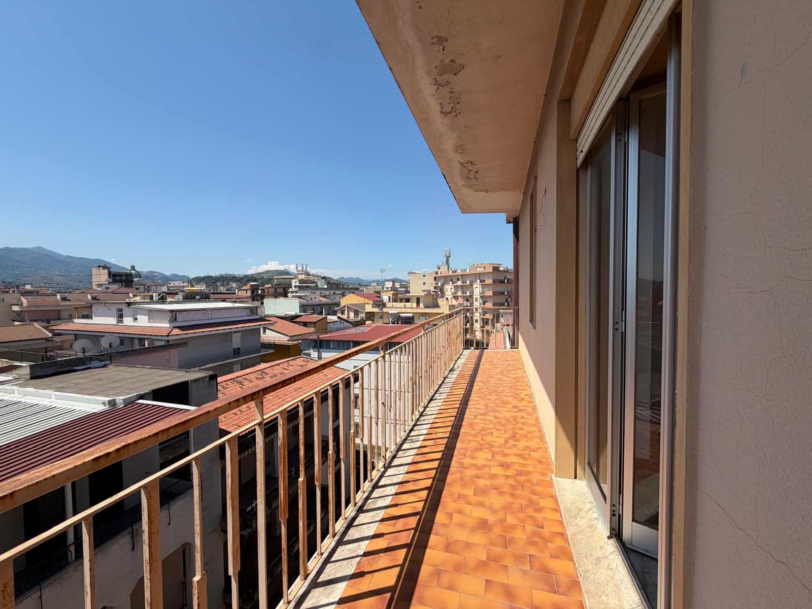 Balcone spazioso con vista sulla città, pavimentato in terracotta, ideale per relax e momenti all'aperto, vicino a servizi e negozi, in un edificio moderno nel centro urbano di NextCasa.