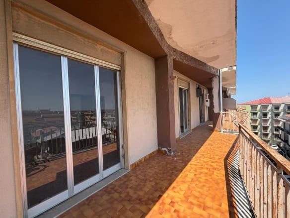 Ampio balcone con vista panoramica su edifici residenziali, pavimentato con piastrelle in terracotta, ideale per relax e socializzazione all'aperto.