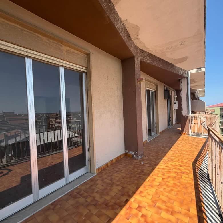 Ampio balcone con vista panoramica su edifici residenziali, pavimentato con piastrelle in terracotta, ideale per relax e socializzazione all'aperto.