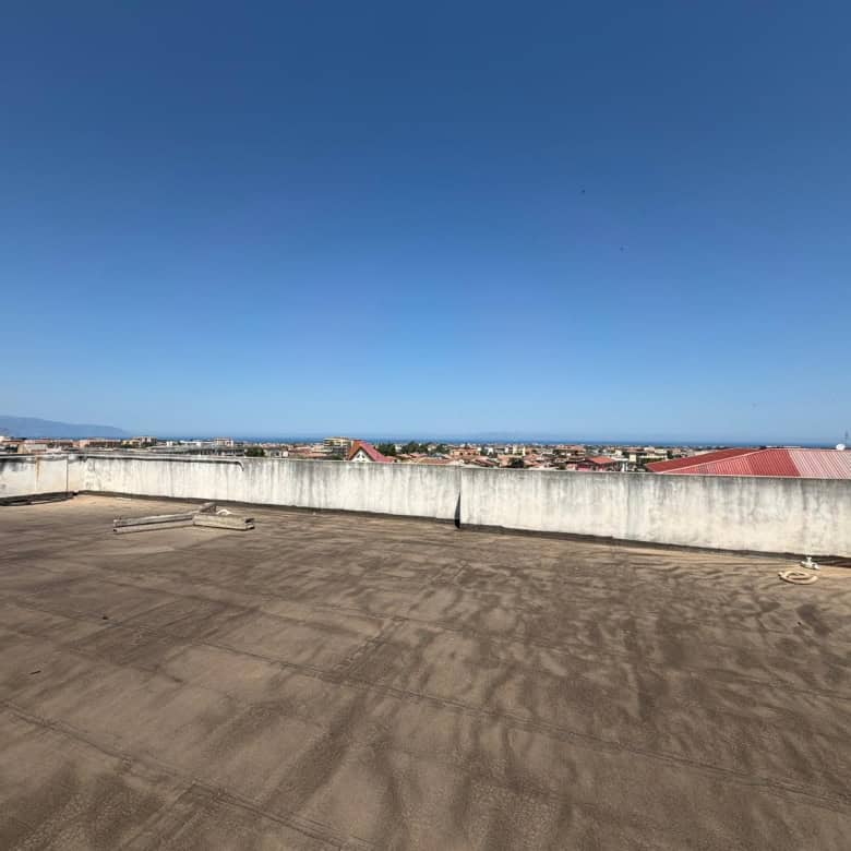 Ampio terrazzo all'aperto con vista panoramica sulla città e sul mare, ideale per relax e socializzazione, con superficie pavimentata e parapetto di sicurezza.
