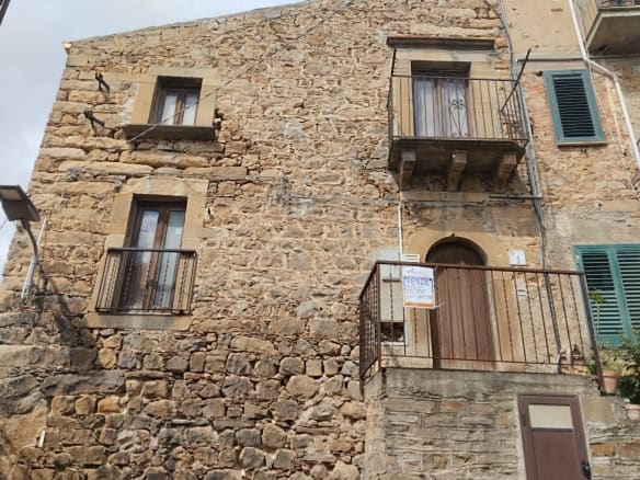 Antico edificio in pietra con finestre e balconi in stile rustico, situato in un quartiere storico italiano. Perfetto esempio di architettura tradizionale e charme locale.