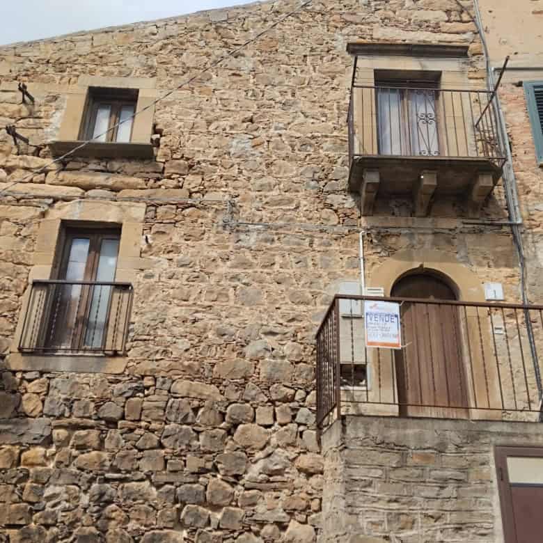 Antico edificio in pietra con finestre e balconi in stile rustico, situato in un quartiere storico italiano. Perfetto esempio di architettura tradizionale e charme locale.