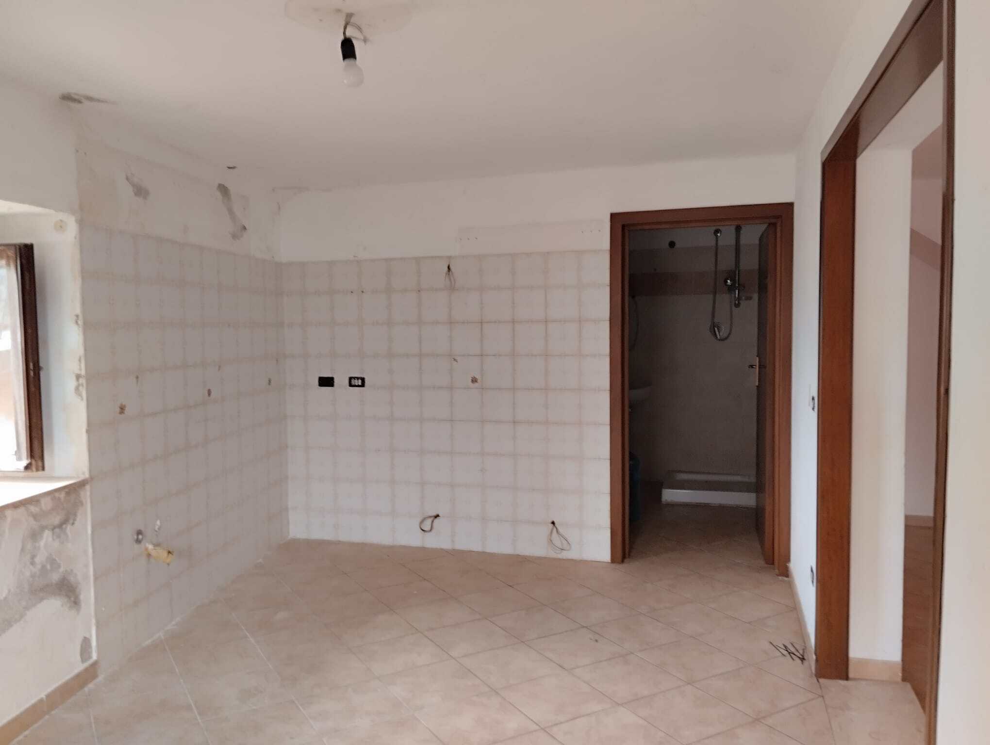 Cucina in fase di ristrutturazione con pareti a piastrelle e spazio vuoto, pronta per essere personalizzata, in un appartamento in fase di rinnovamento.