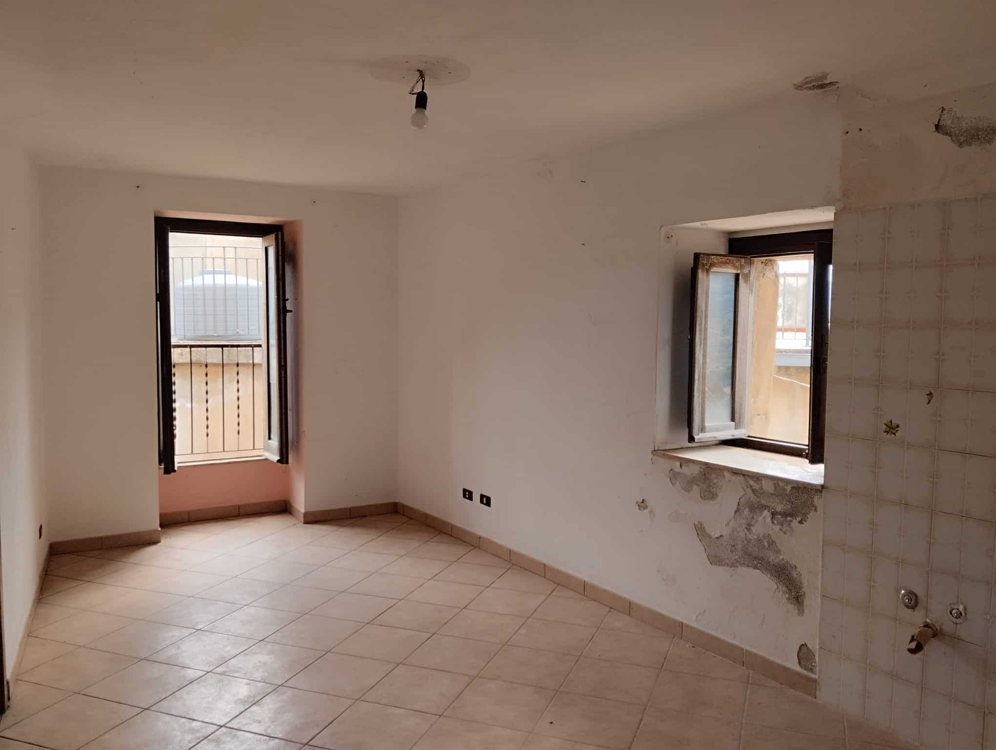 Interno di un appartamento in fase di ristrutturazione con pareti da rifinire e finestre aperte, pronto per personalizzazione e arredo.