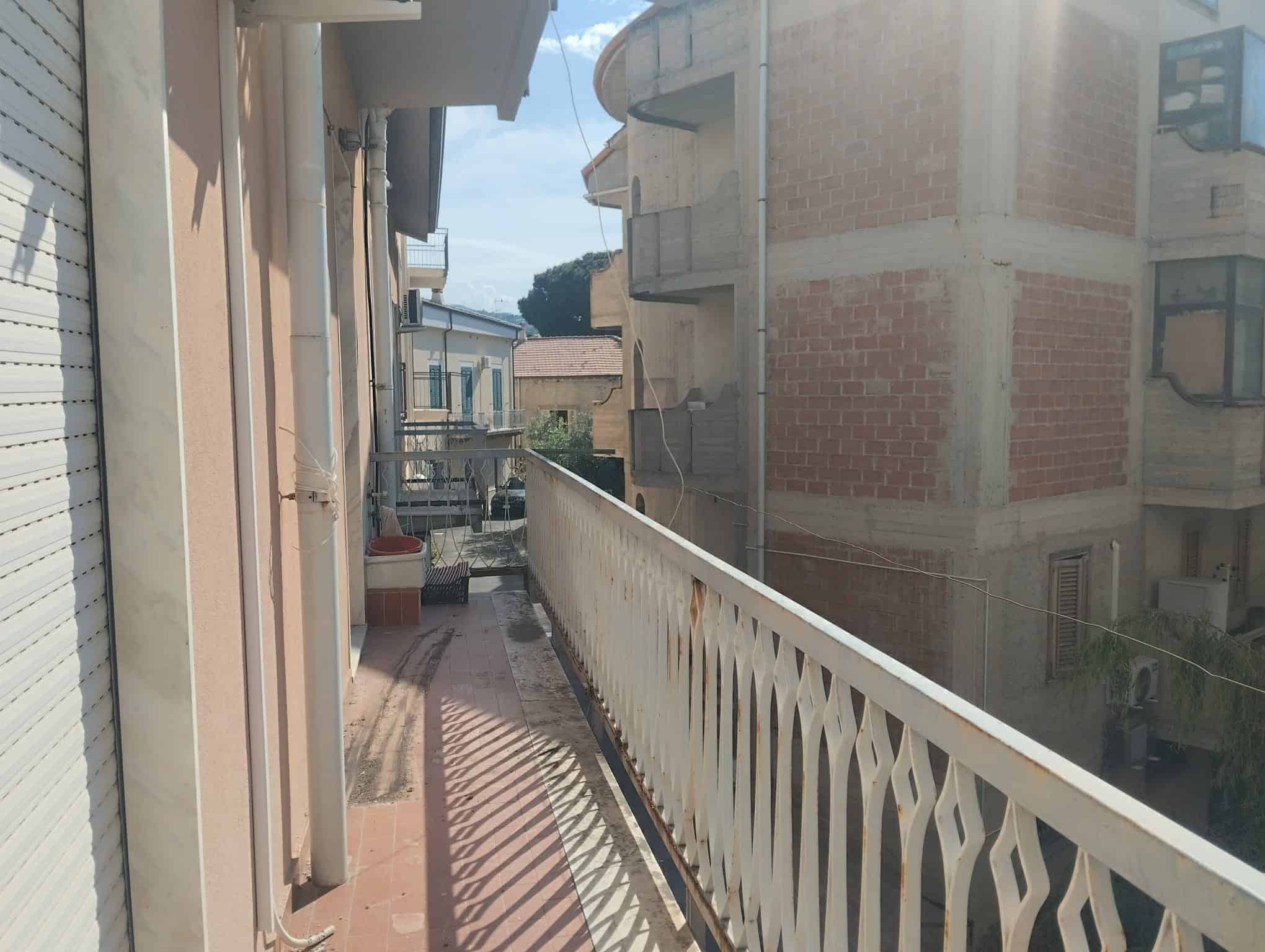 Balcone di un appartamento con ringhiera decorativa, vista su edifici residenziali e cielo sereno, in un contesto urbano tranquillo, ideale per relax e momenti di svago all'aperto.