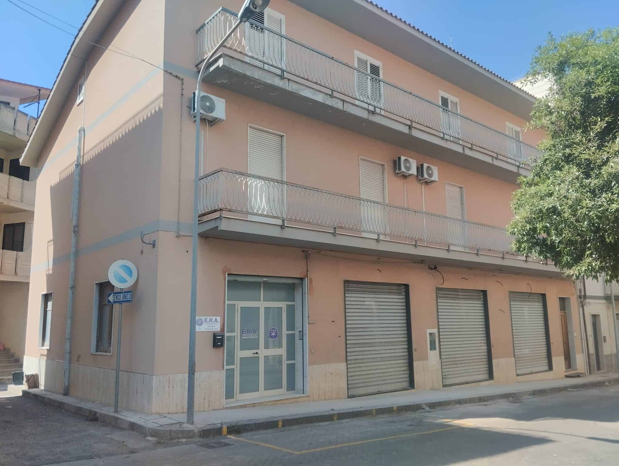 Ampio edificio residenziale con negozi al piano terra, balconi e aria condizionata, situato in zona urbana tranquilla, ideale per investimento immobiliare o abitazione familiare.