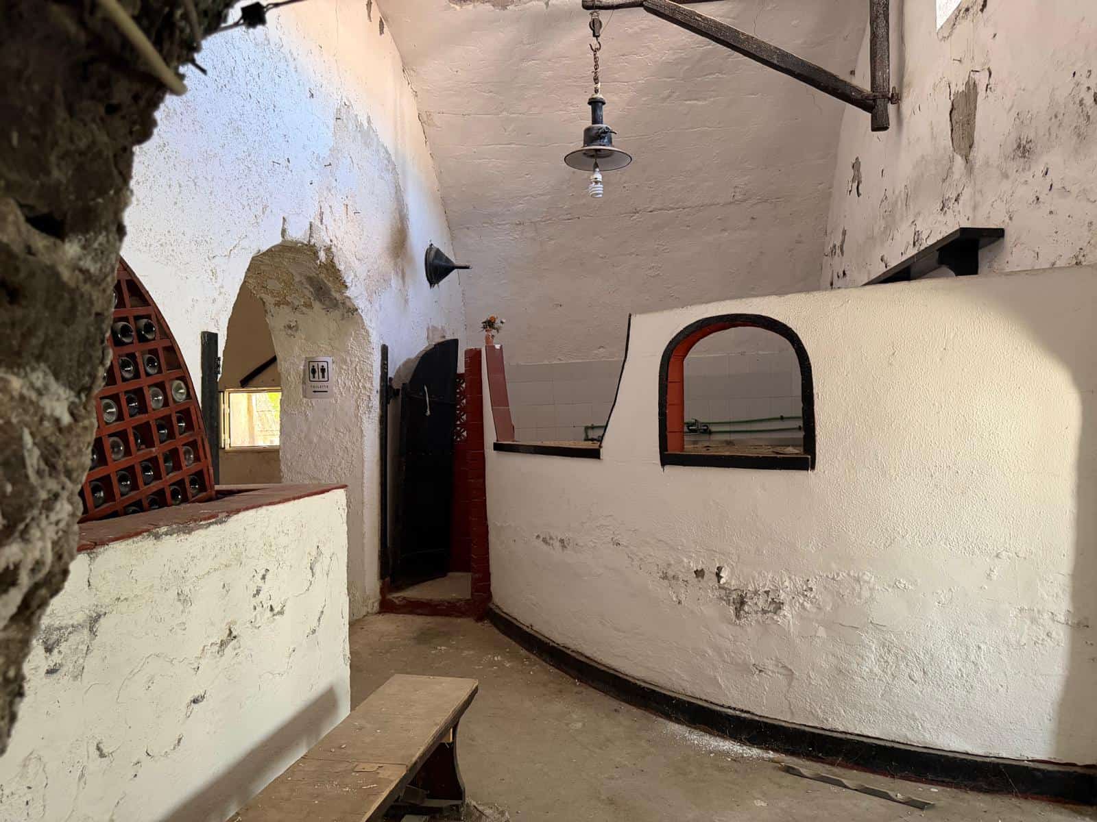 Interno di un cortile tradizionale con pareti bianche, archi e illuminazione semplice, stile rustico e autentico.