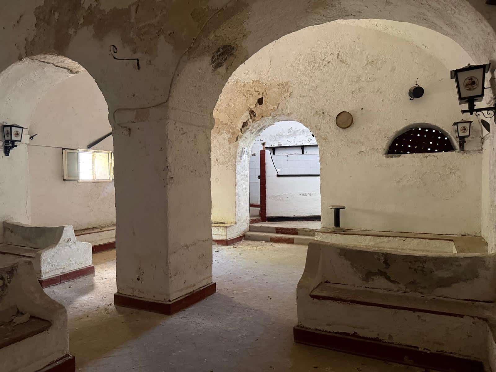 Antico ambiente in pietra con archi e nicchie, caratterizzato da pareti bianche e dettagli rustici, ideale per ambienti storici o spazi di charme.