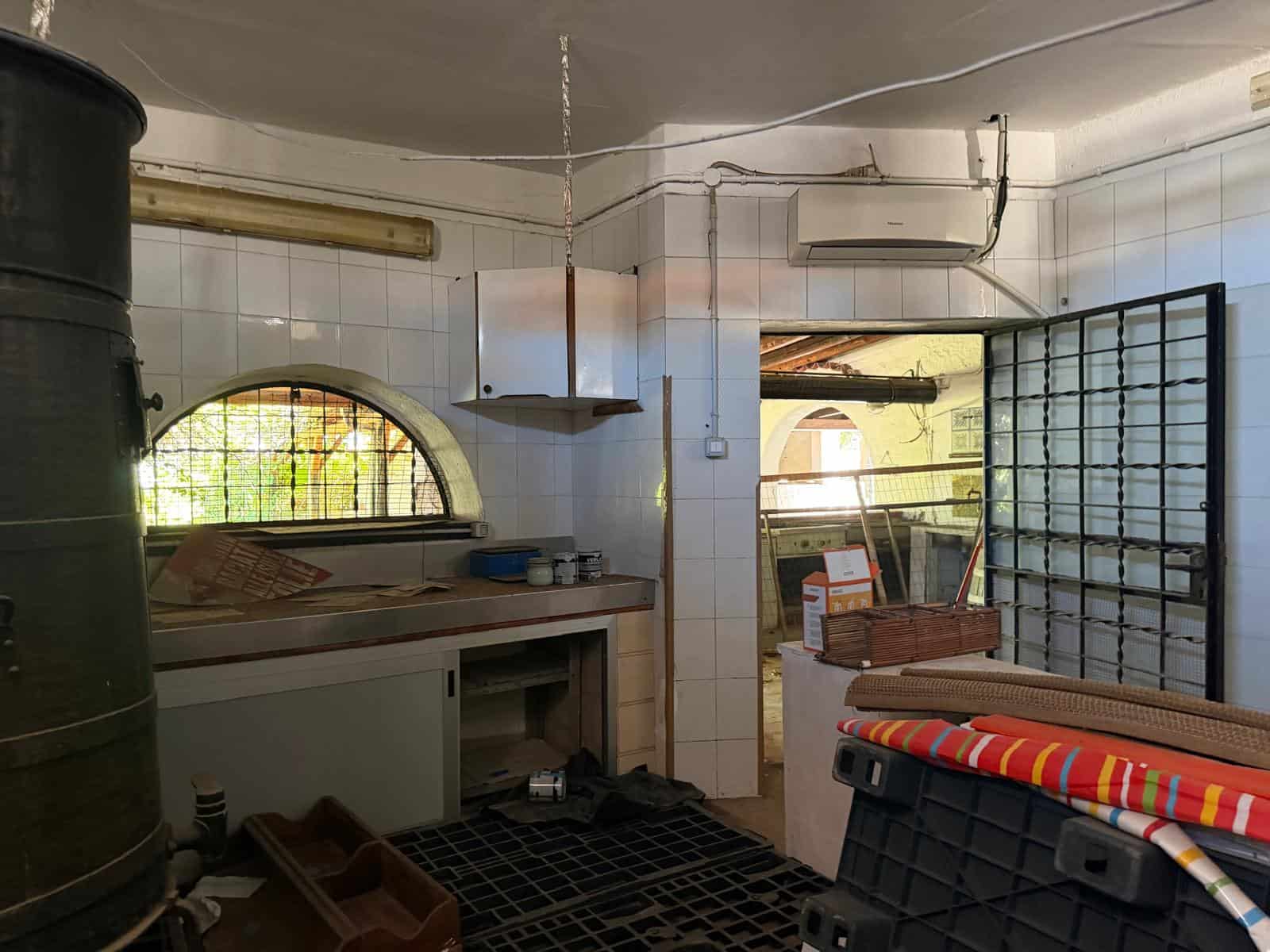 Ampia cucina con pareti bianche, forno e piano di lavoro in ambiente domestico, con accessori e utensili pronti per la preparazione dei pasti, illuminata dalla luce naturale attraverso una finestra ad.