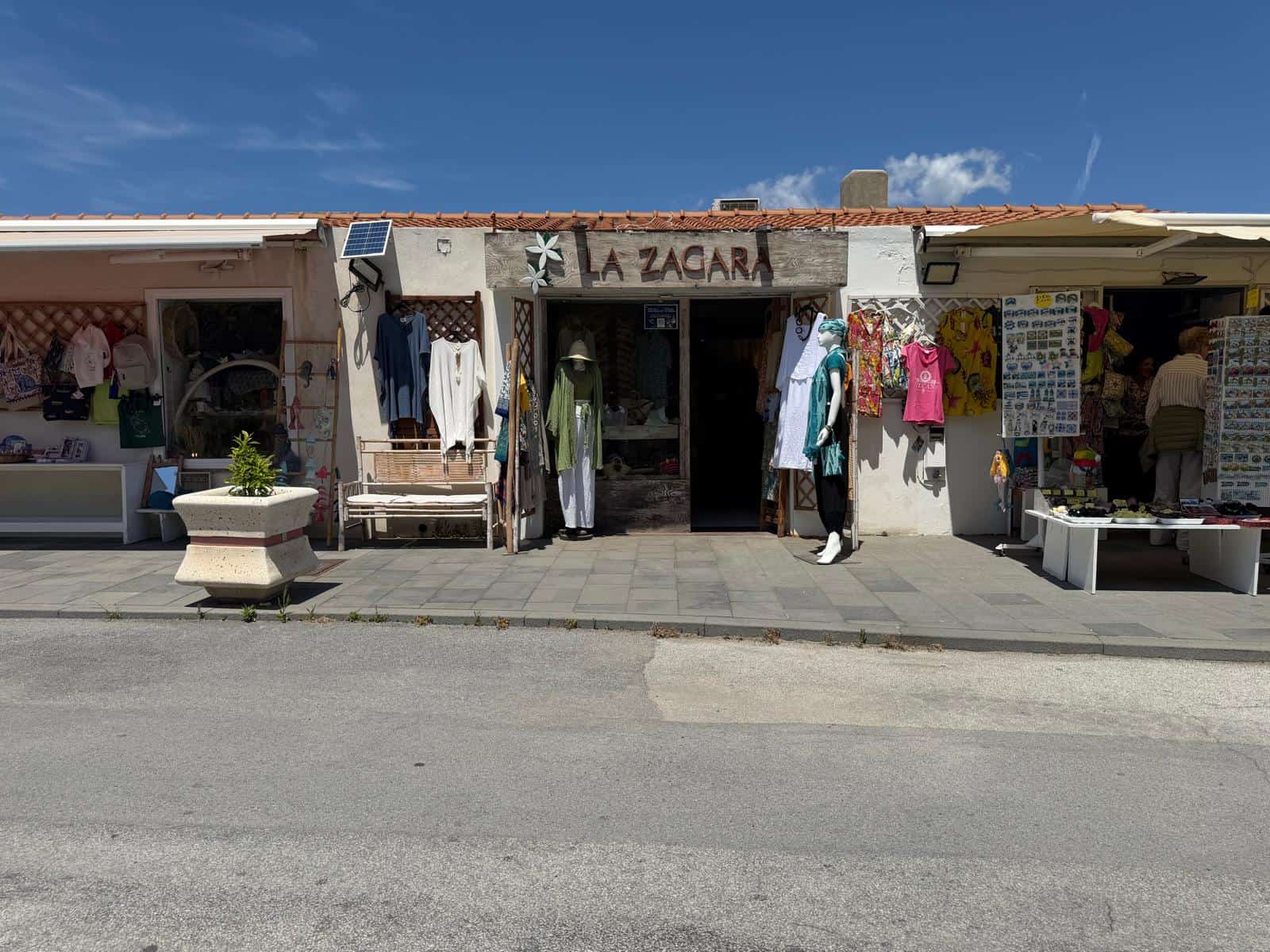 Vestito e accessori in vendita presso il negozio La Zagara, con abbigliamento estivo, decorazioni e souvenir, situato in una zona pedonale soleggiata, ideale per shopping e passeggiate estive.