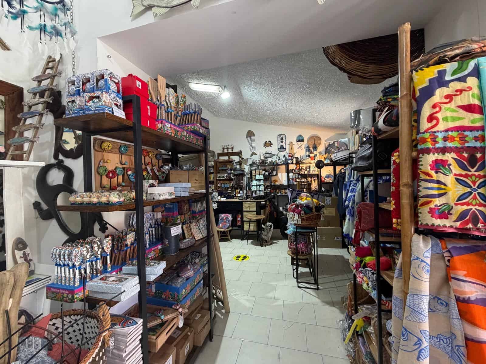 Cestino di oggetti artigianali e decorativi in un negozio di souvenir, con scaffali pieni di articoli colorati e vari, in un ambiente accogliente e ben organizzato.