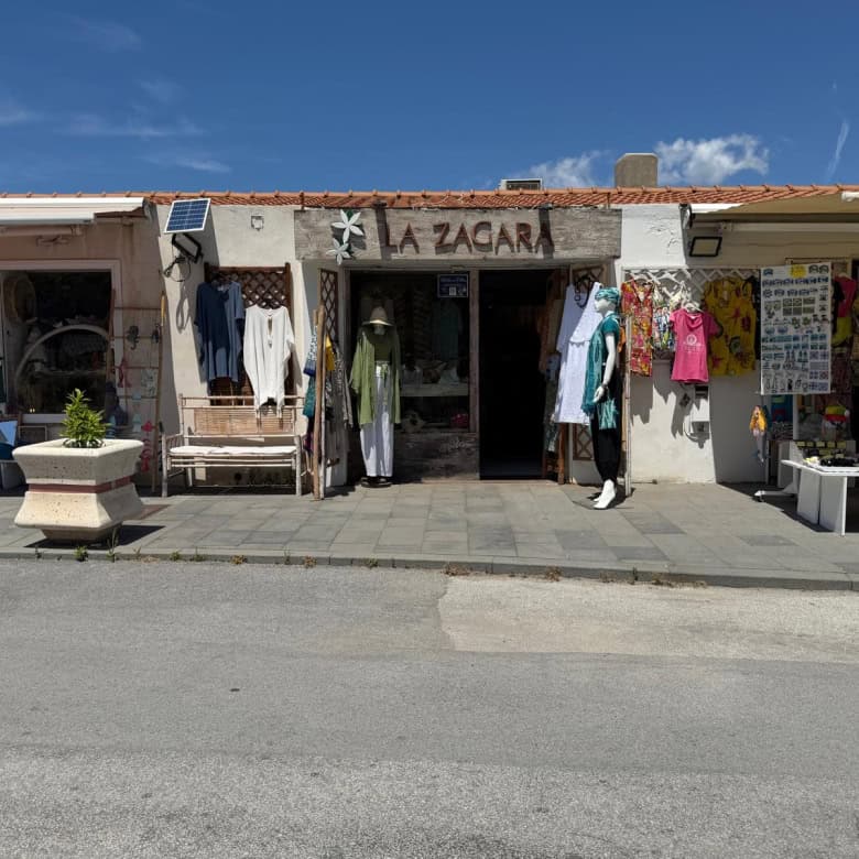 Vestito e accessori in vendita presso il negozio "La Zagara" con esposizione di abbigliamento e souvenir in un ambiente all'aperto.