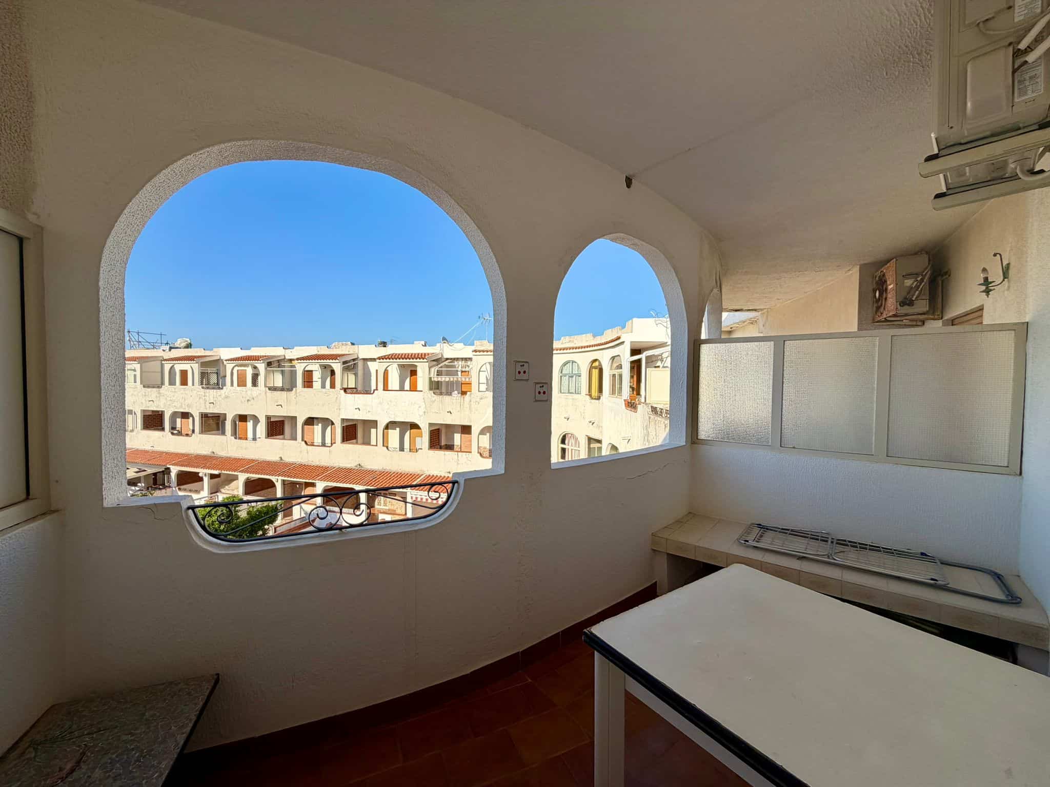 Vista panoramica di un balcone con archi, con vista su edifici residenziali e cielo azzurro, ideale per immagini di immobili e appartamenti in vendita o affitto a NextCasa.