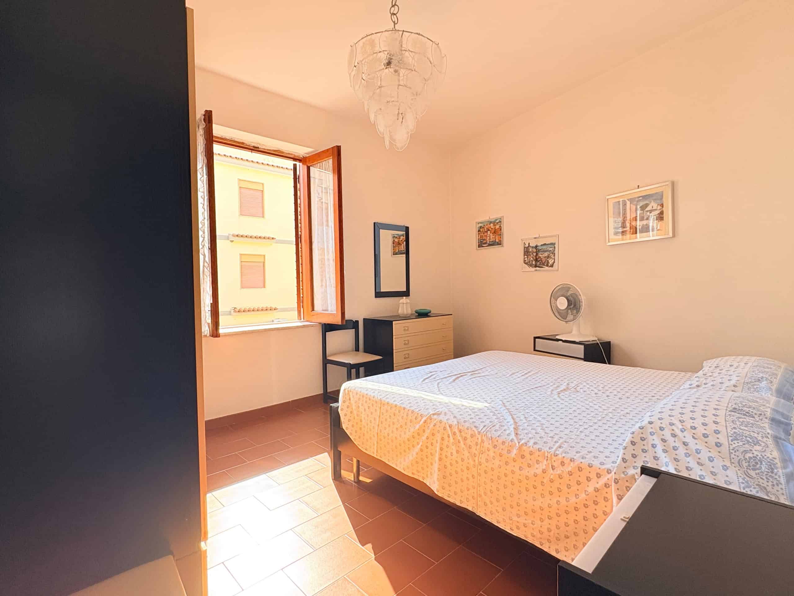 Ampia camera da letto luminosa con finestra aperta, arredi moderni e decorazioni eleganti, ideale per soggiorni confortevoli e rilassanti in un ambiente accogliente.