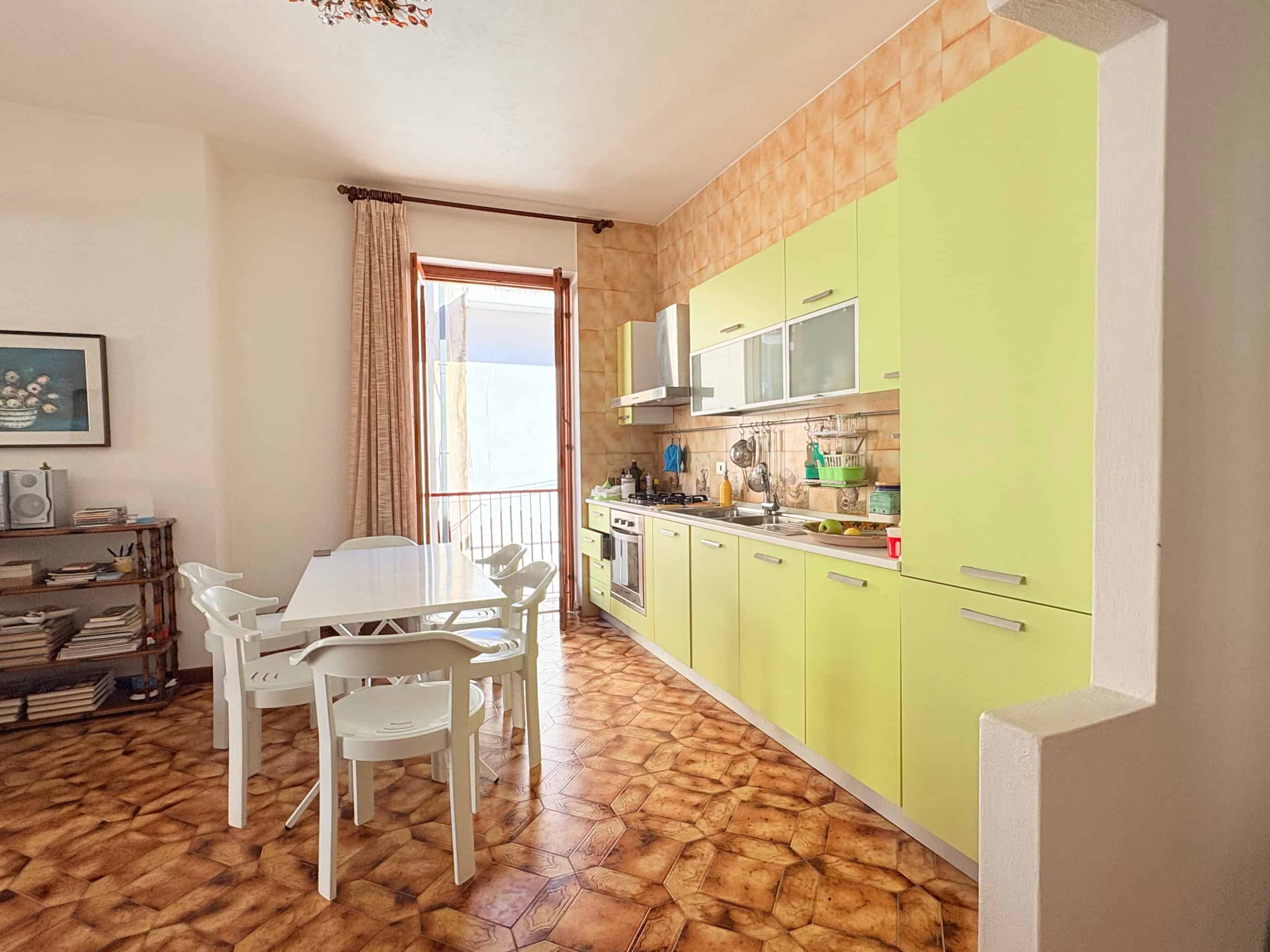 Cucina moderna con mobili verde lime, tavolo bianco e accessori, in un appartamento luminoso e accogliente.