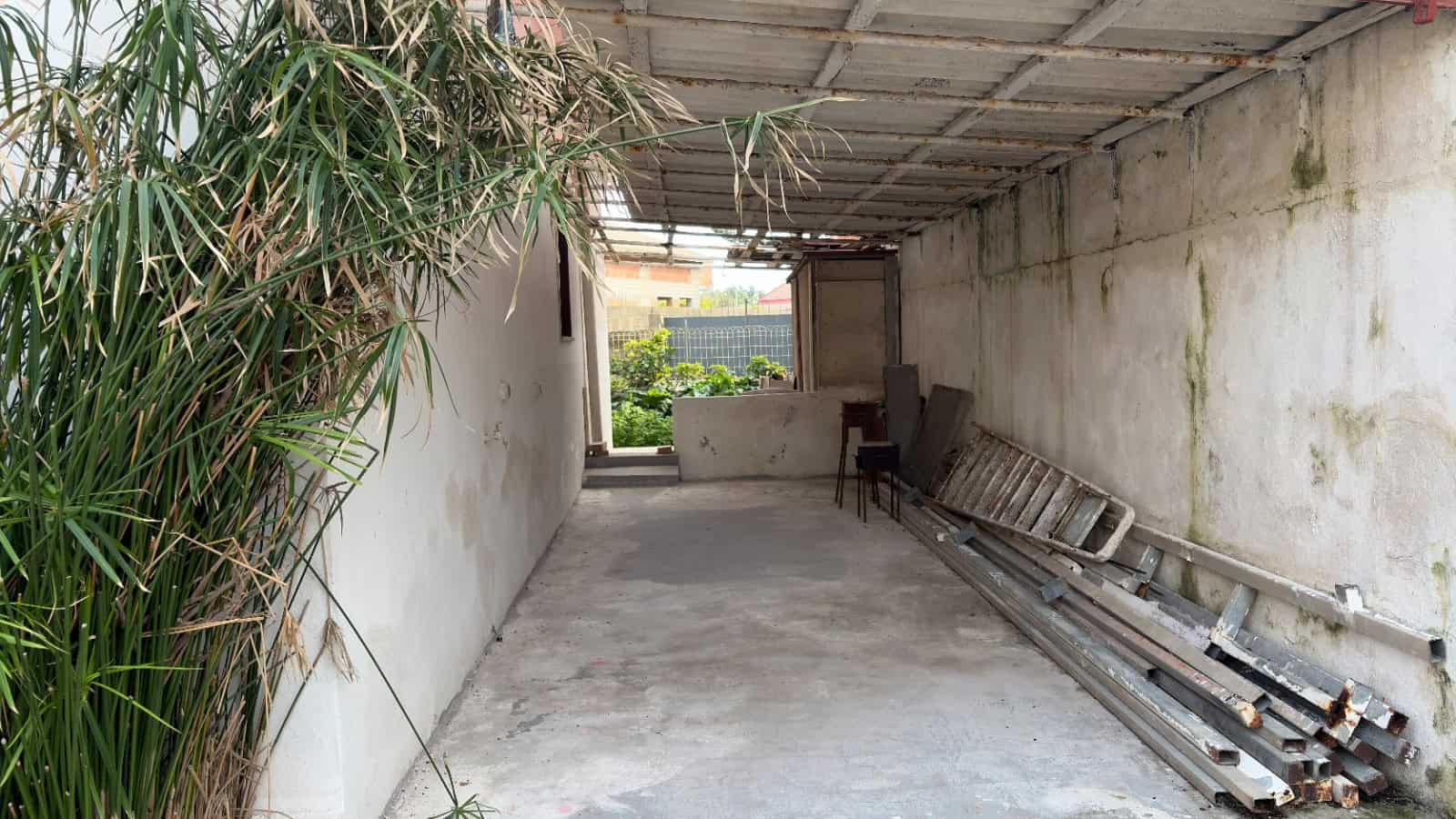 Cancello di garage o deposito in un ambiente semi-industriale con pareti in cemento e attrezzature di lavoro, ideale per ristrutturazioni o magazzino.