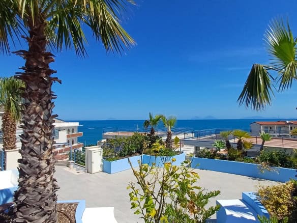 Vista panoramica sul mare con palme tropicali e terrazza soleggiata, ideale per case vacanza e immobili di lusso in località costiere. Perfetta per investimenti immobiliari vicino al mare.