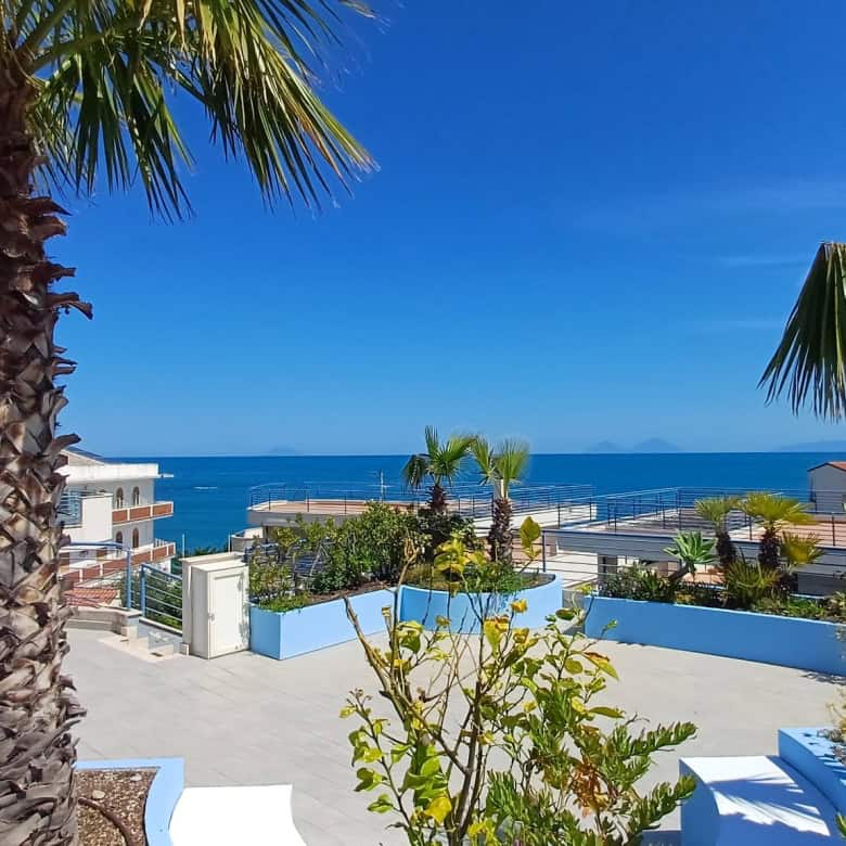 Vista panoramica sul mare con palme tropicali e terrazza soleggiata, ideale per case vacanza e immobili di lusso in località costiere. Perfetta per investimenti immobiliari vicino al mare.