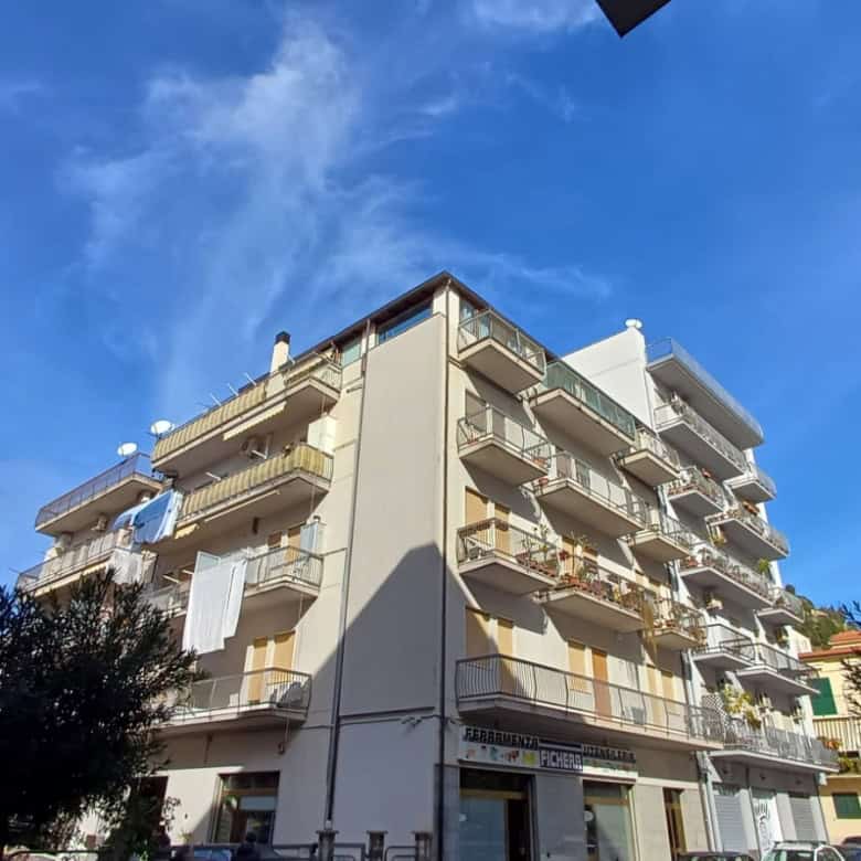 Appartamento residenziale con balconi e aria aperta, edificio moderno in zona urbana soleggiata, cielo blu e alberi circostanti, ideale per investimento immobiliare o abitazione privata.