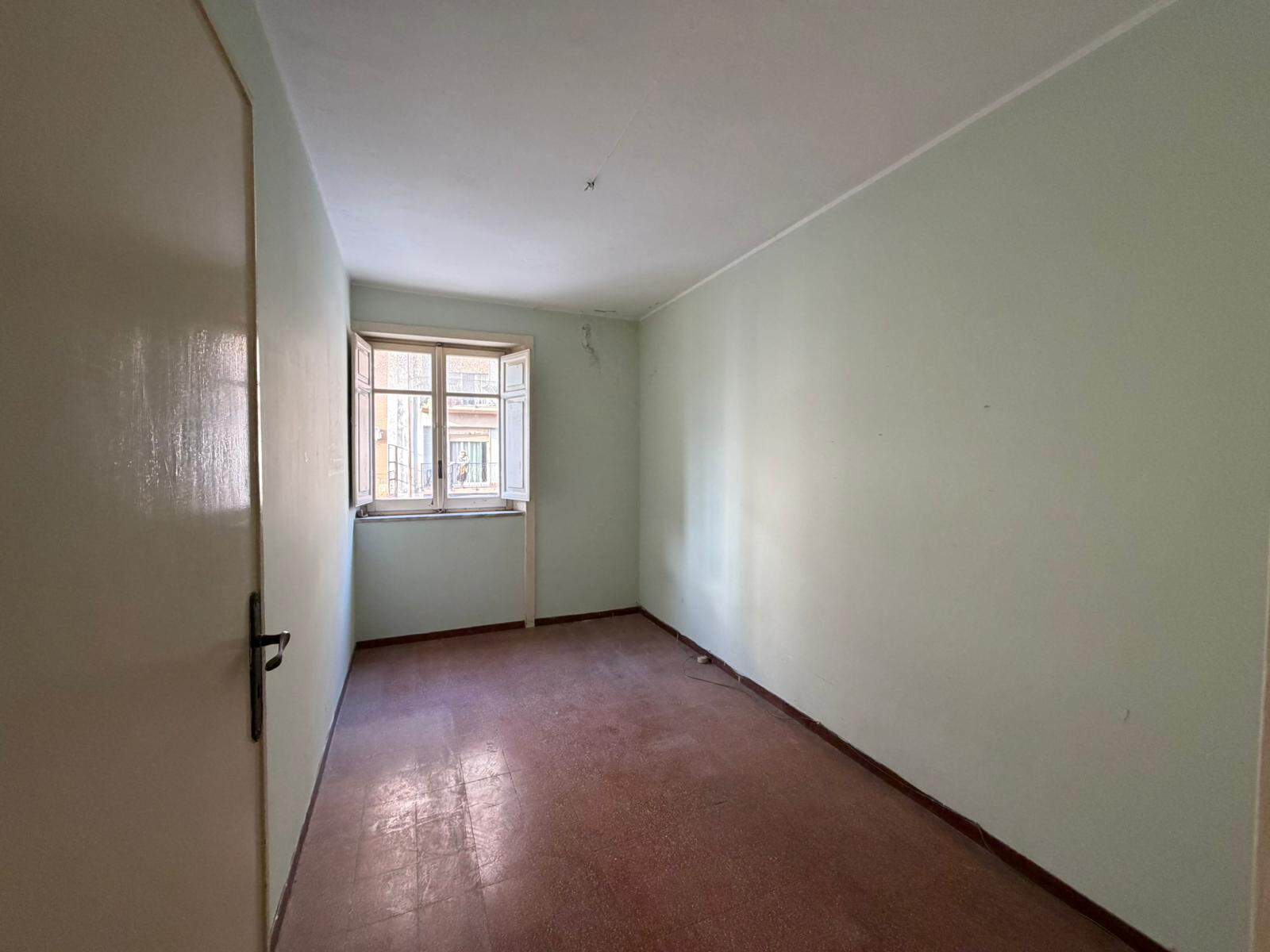 Ampia stanza vuota con pareti verdi chiaro e finestra che lascia entrare luce naturale, ideale per ristrutturazione e personalizzazione, perfetta come spazio residenziale o ufficio.