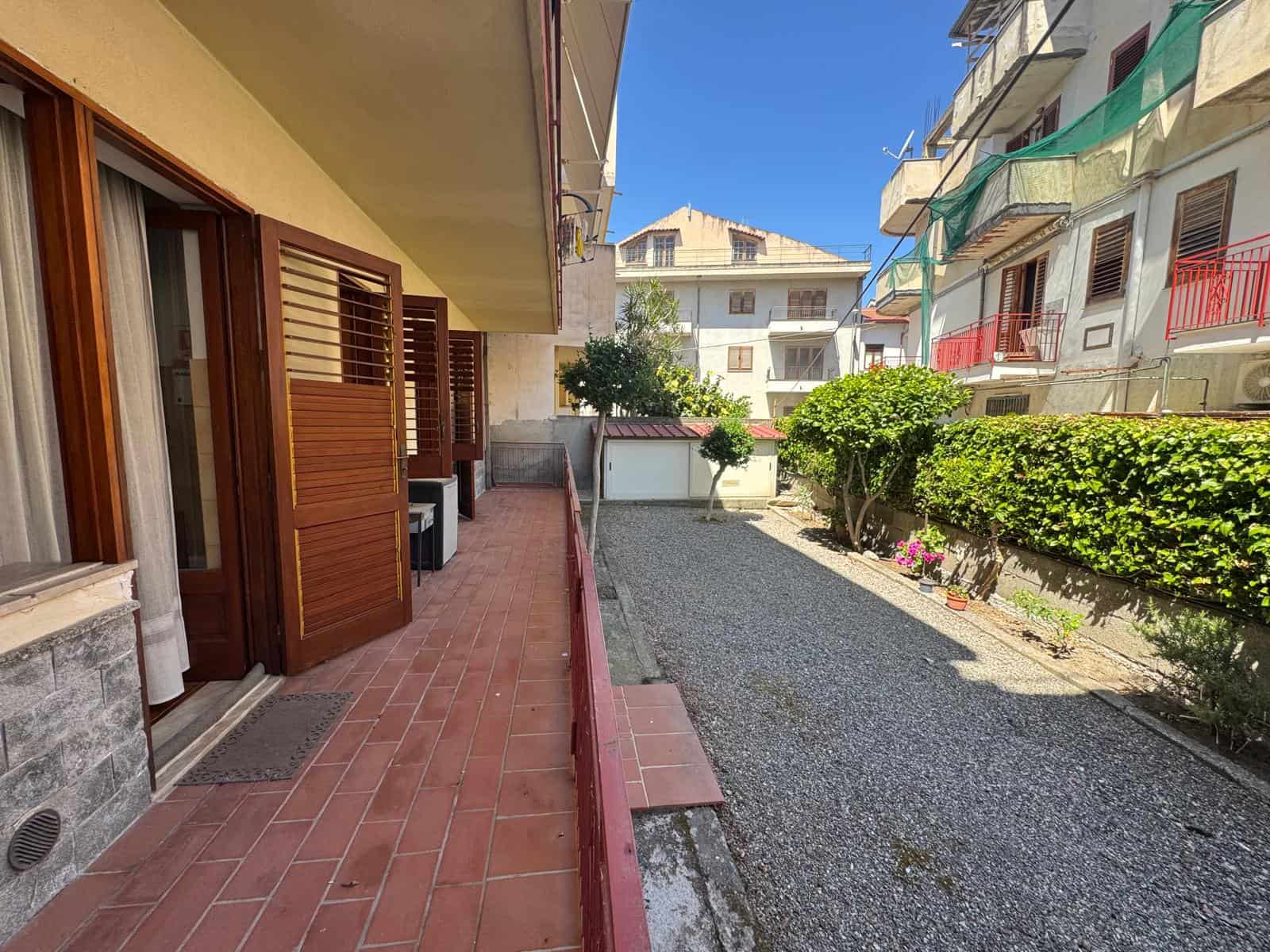 Balcone e giardino condominiale con piante e spazio esterno.