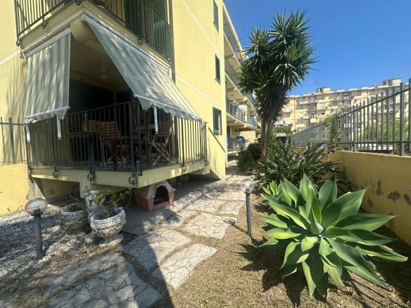 Balcone con area verde e piante succulente, vista su edificio residenziale a Milazzo, ME.