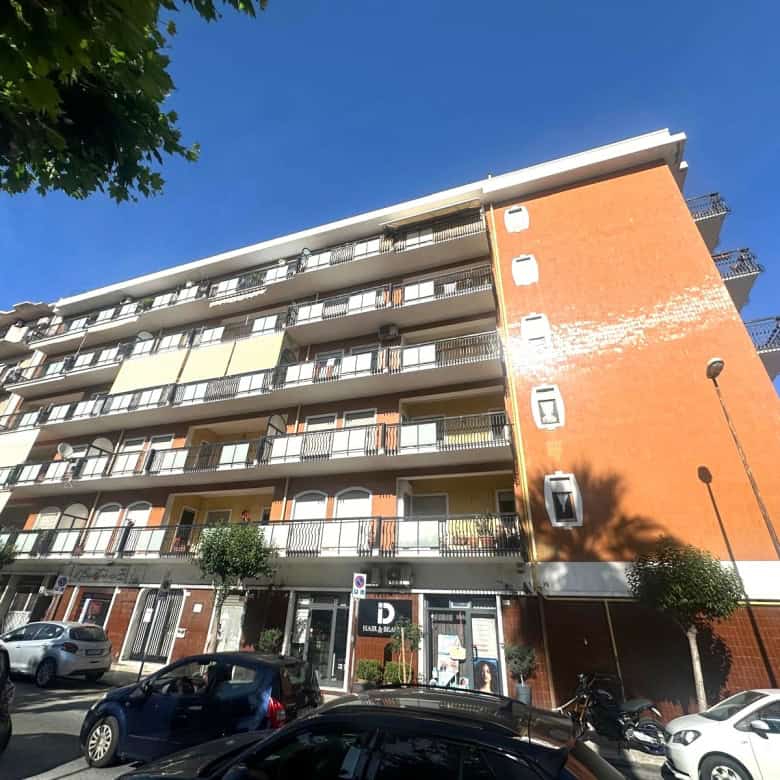 Edificio residenziale moderno con balconi e parcheggio, vista frontale, in zona urbana.