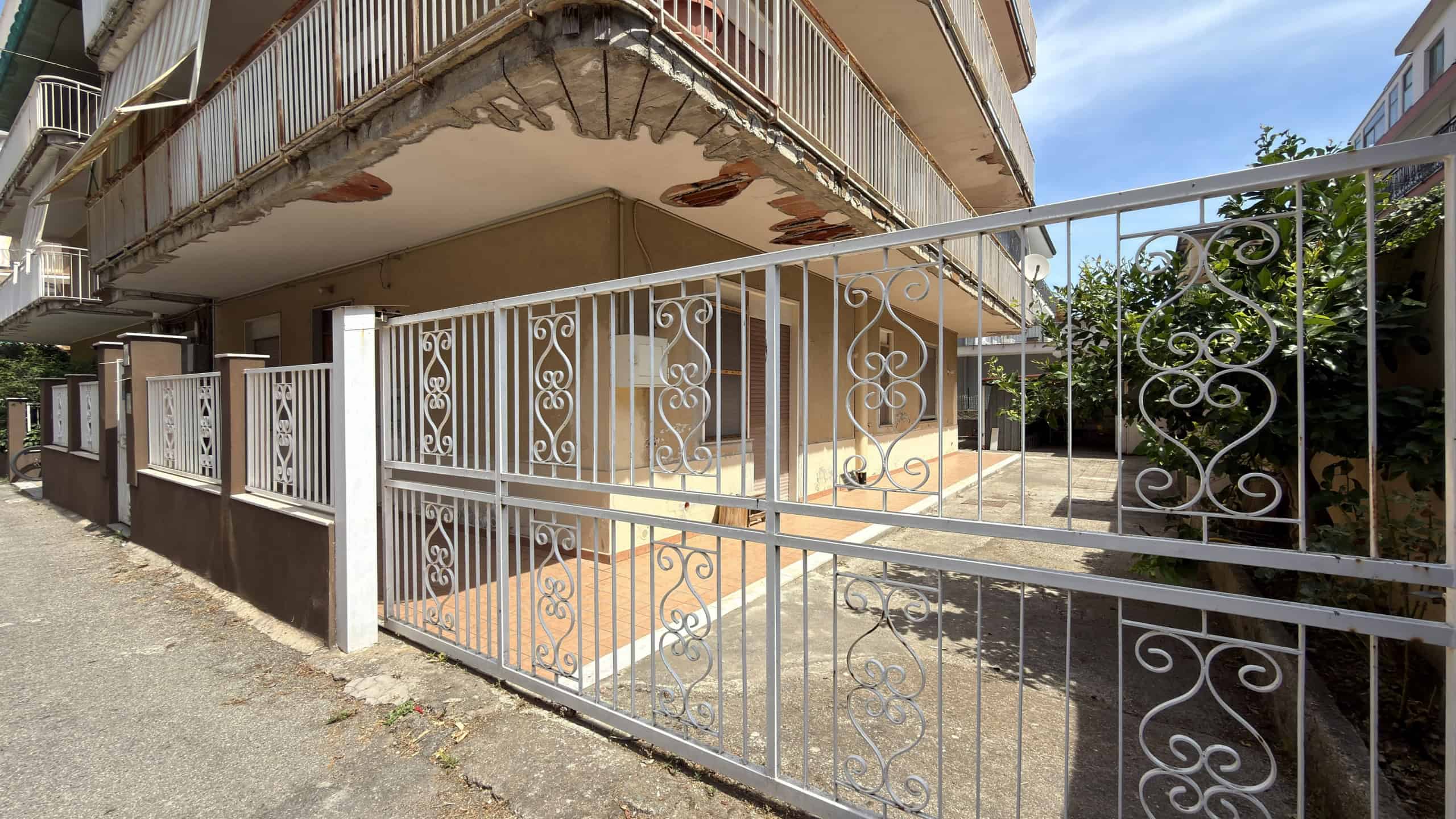 Balcone e cancello in ferro battuto di un appartamento residenziale a NextCasa, con dettagli decorativi eleganti e struttura in metallo bianco.