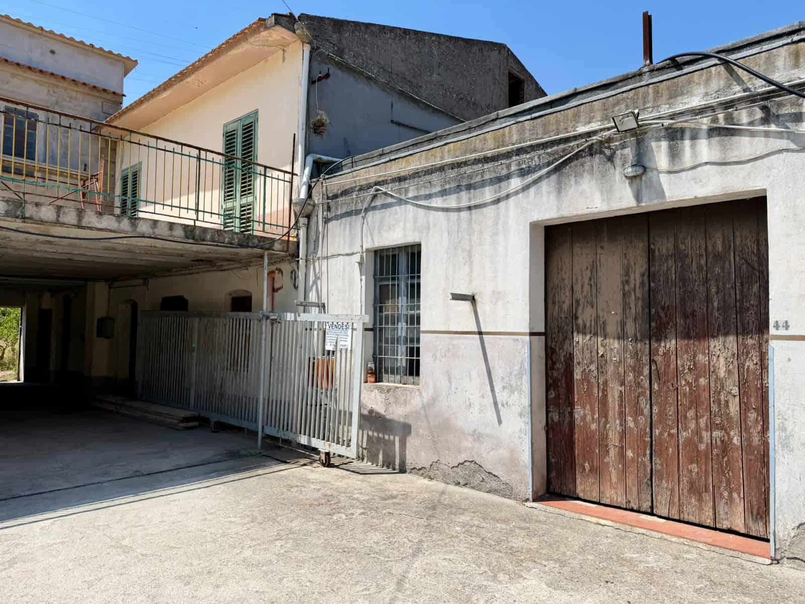 Edificio residenziale con garage in zona urbana, struttura in cemento e legno, con accesso carrabile e spazio di parcheggio esterno, in un quartiere tranquillo.