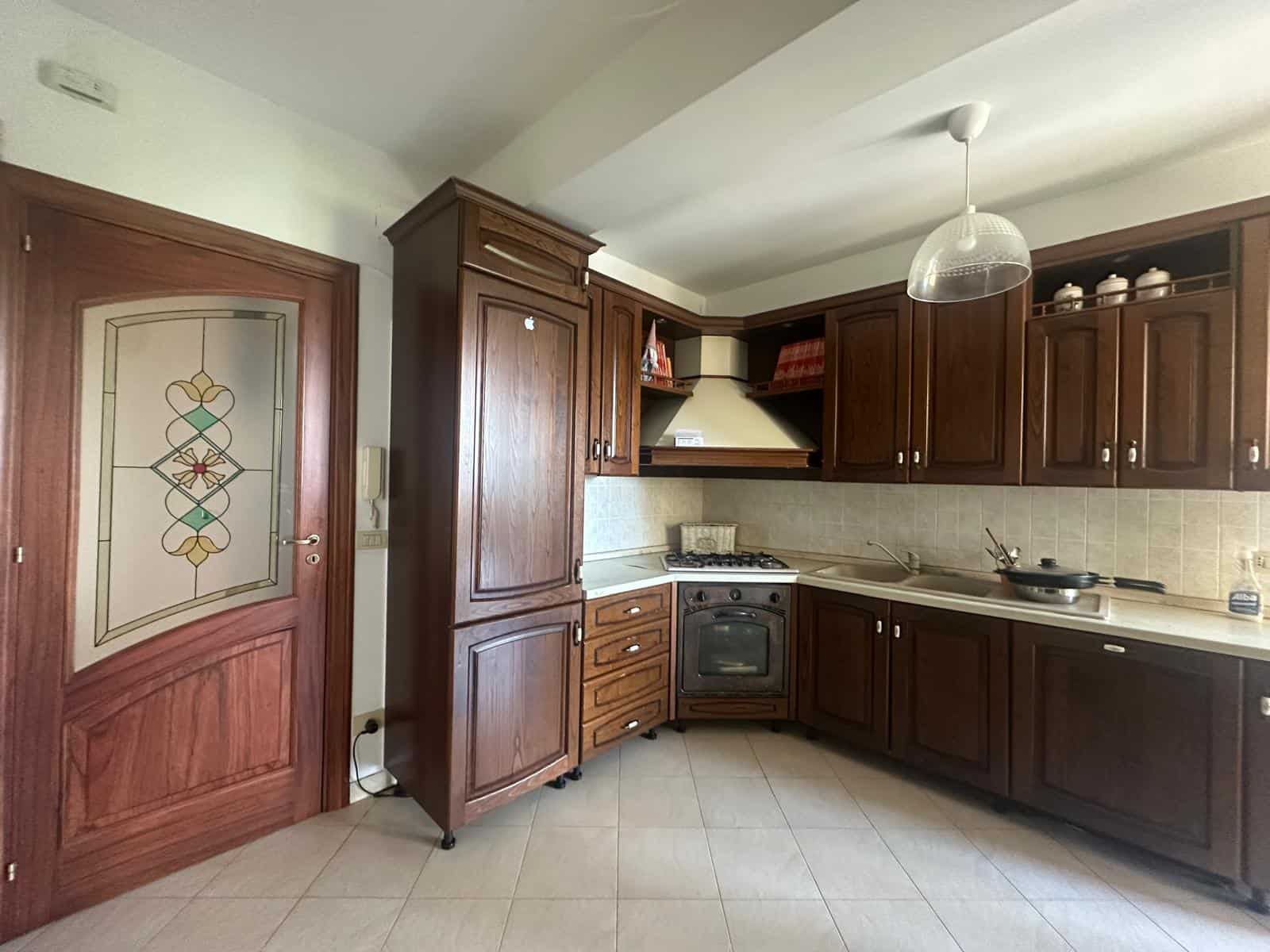 Cucina abitabile in appartamento a Milazzo con mobili in legno scuro e piano cottura a gas.
