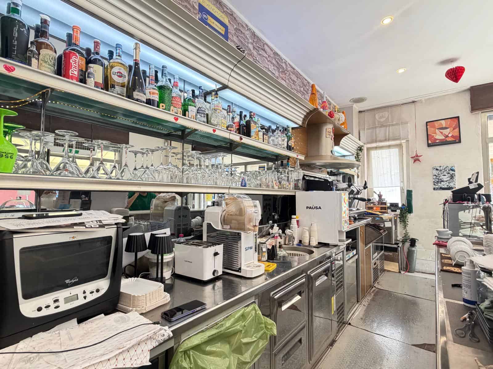 Interno di un bar con bancone, bottiglie di alcolici e attrezzature da bar, ambiente luminoso e accogliente a Milazzo.