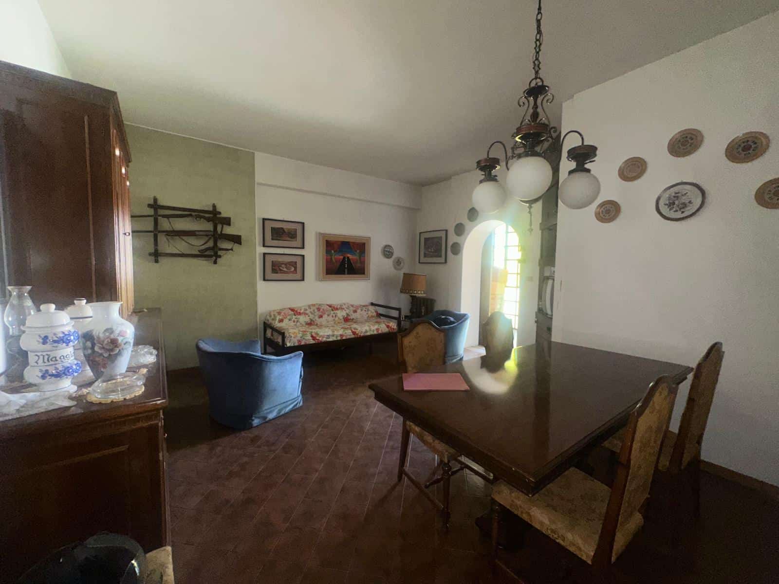 Interno di soggiorno con mobili d'epoca, pareti decorate e illuminazione calda, ideale per vivere momenti di relax e convivialità in un ambiente accogliente.