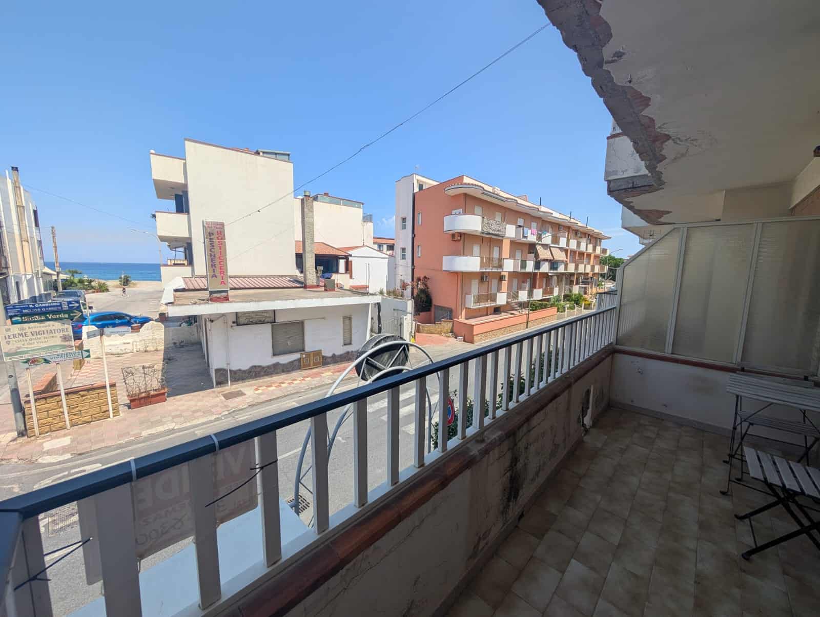 Balcone di un appartamento con vista sul mare e sulle case vicine, in zona residenziale.