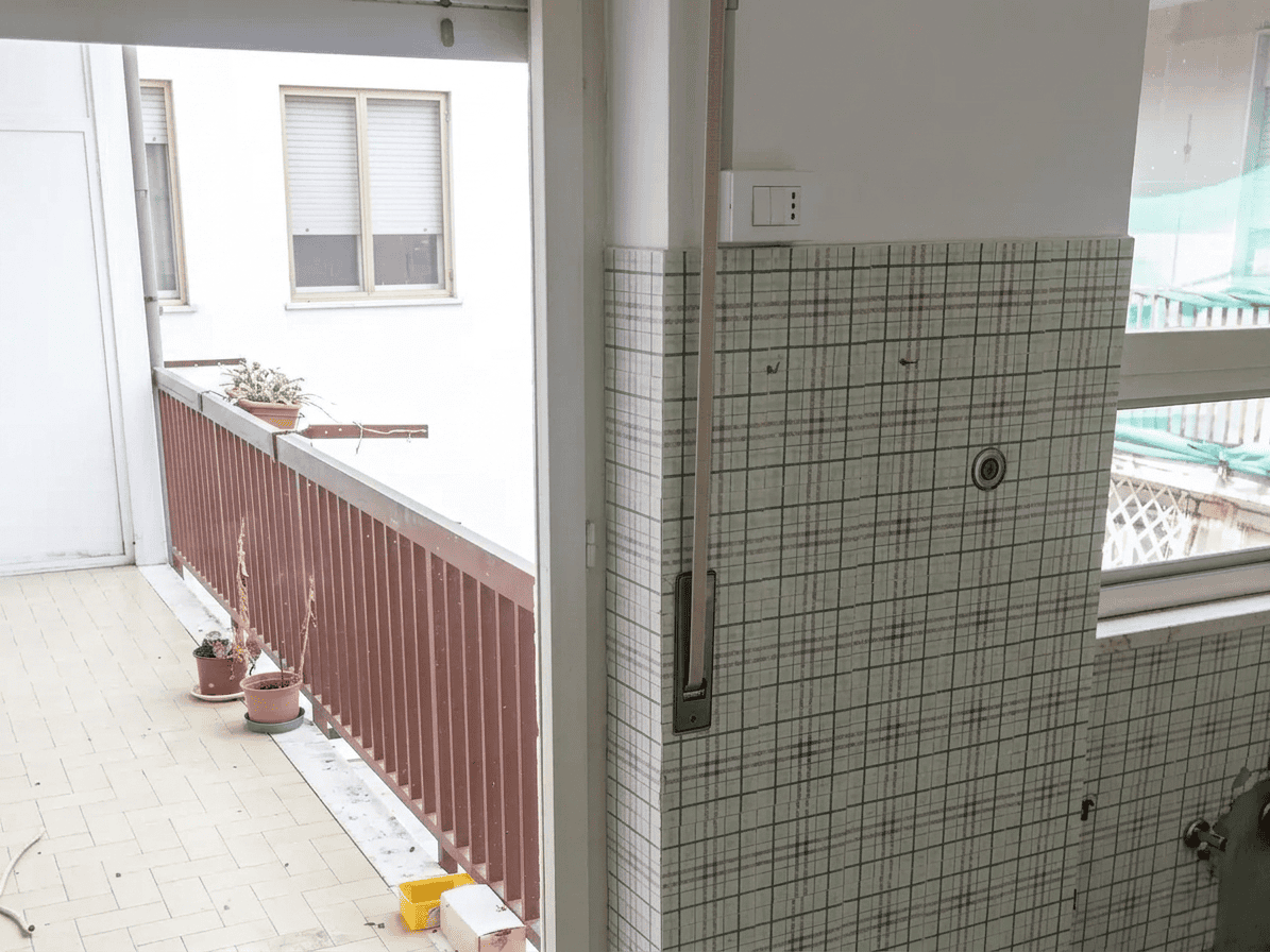 Balcone con ringhiera in legno e piante in vaso, vista su edificio urbano.