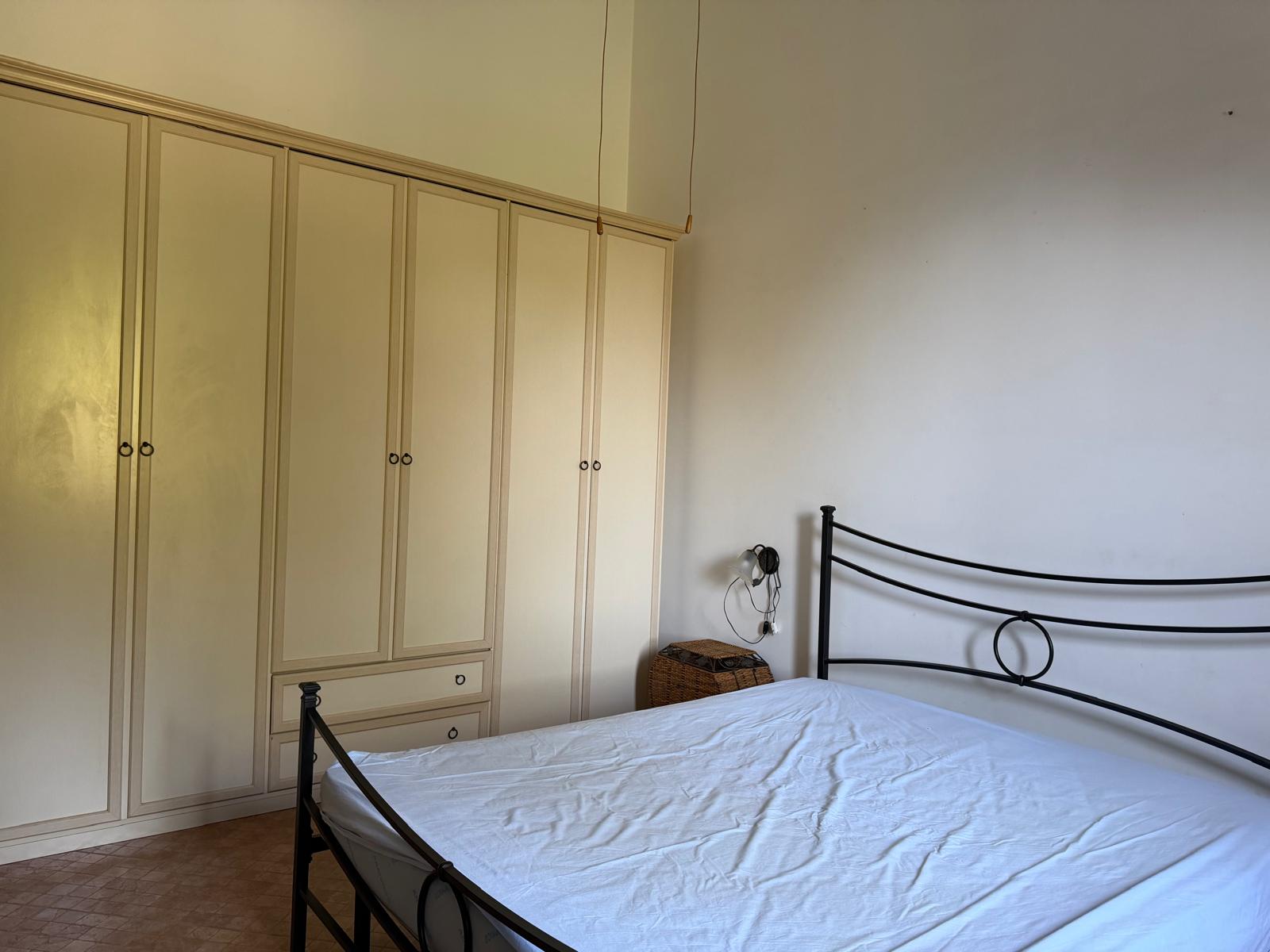 Camera da letto con armadio a muro e letto in ferro battuto, ambiente luminoso e accogliente, stile semplice e funzionale.