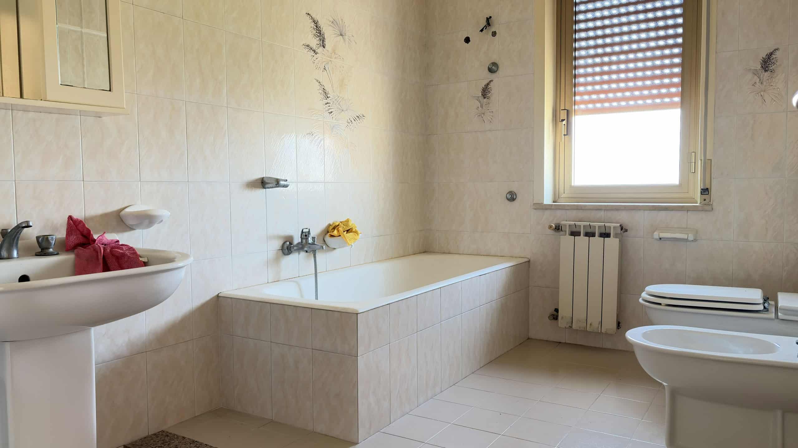 Bagno con vasca, bidet e finestra, arredamento semplice e funzionale, in stile classico.