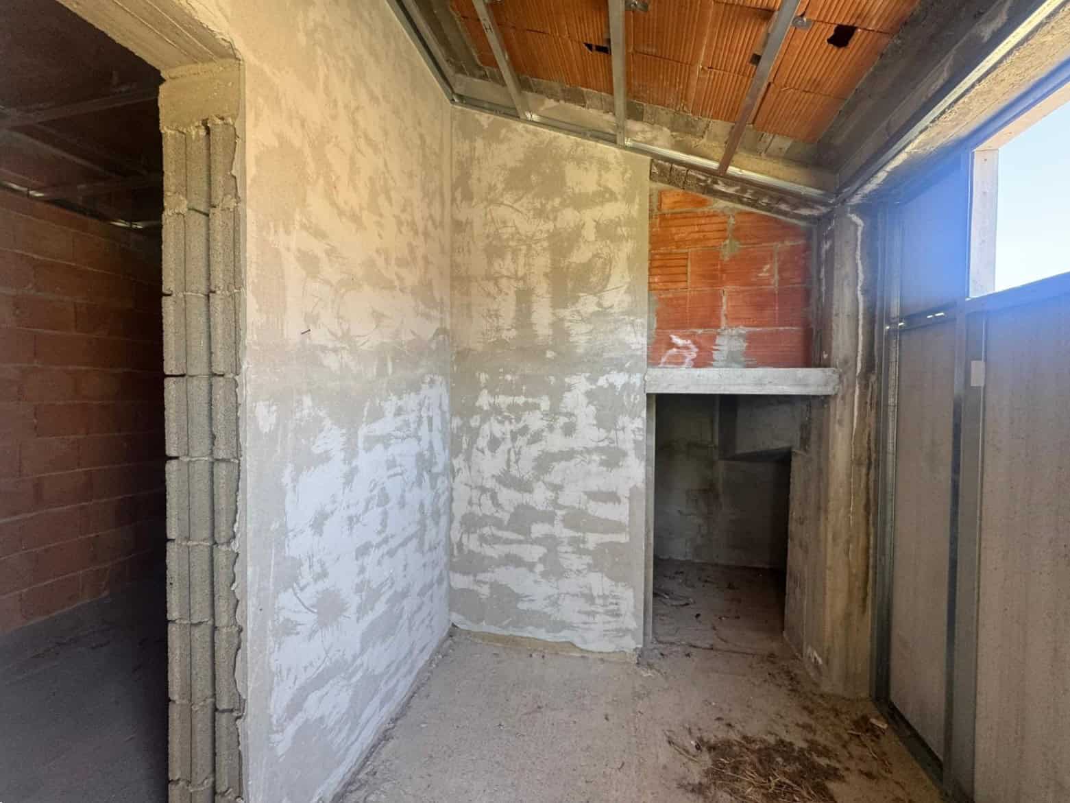 Interno di un edificio in costruzione con pareti in fase di finitura e finestre installate.